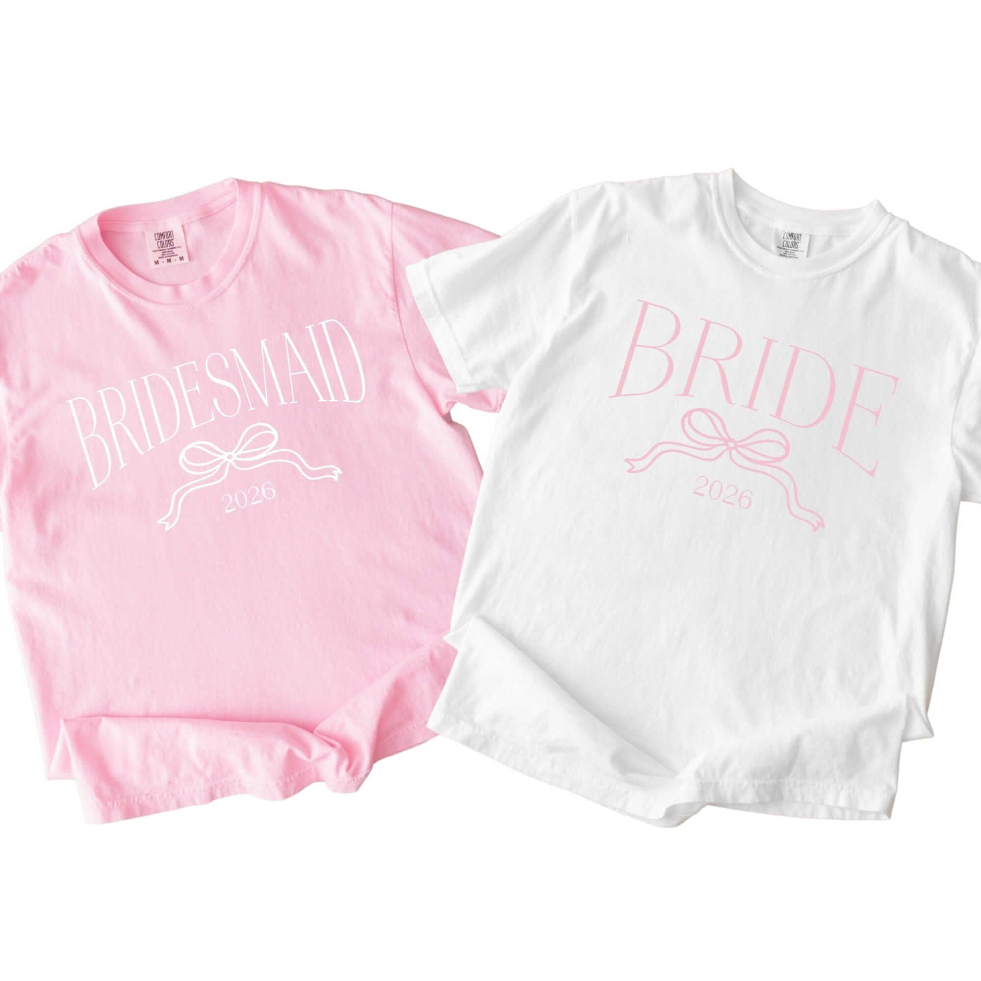 A pink t-shirt and a white t-shirt, both featuring a decorative bow graphic, designed for a bridal party.