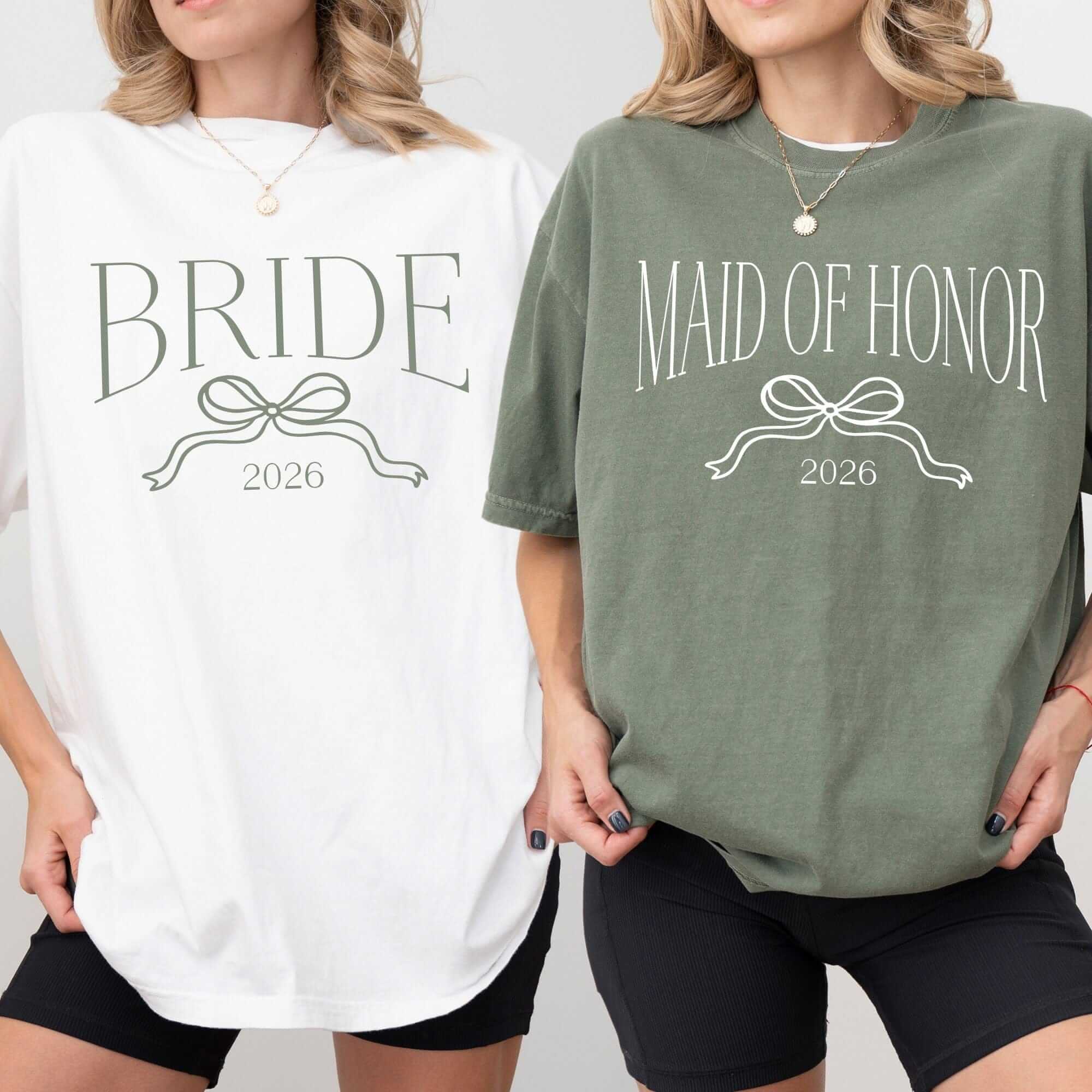 Two oversized, short-sleeved t-shirts, one white with a green bow graphic and one olive green with a white bow graphic, made from a soft, comfortable fabric for a wedding party.