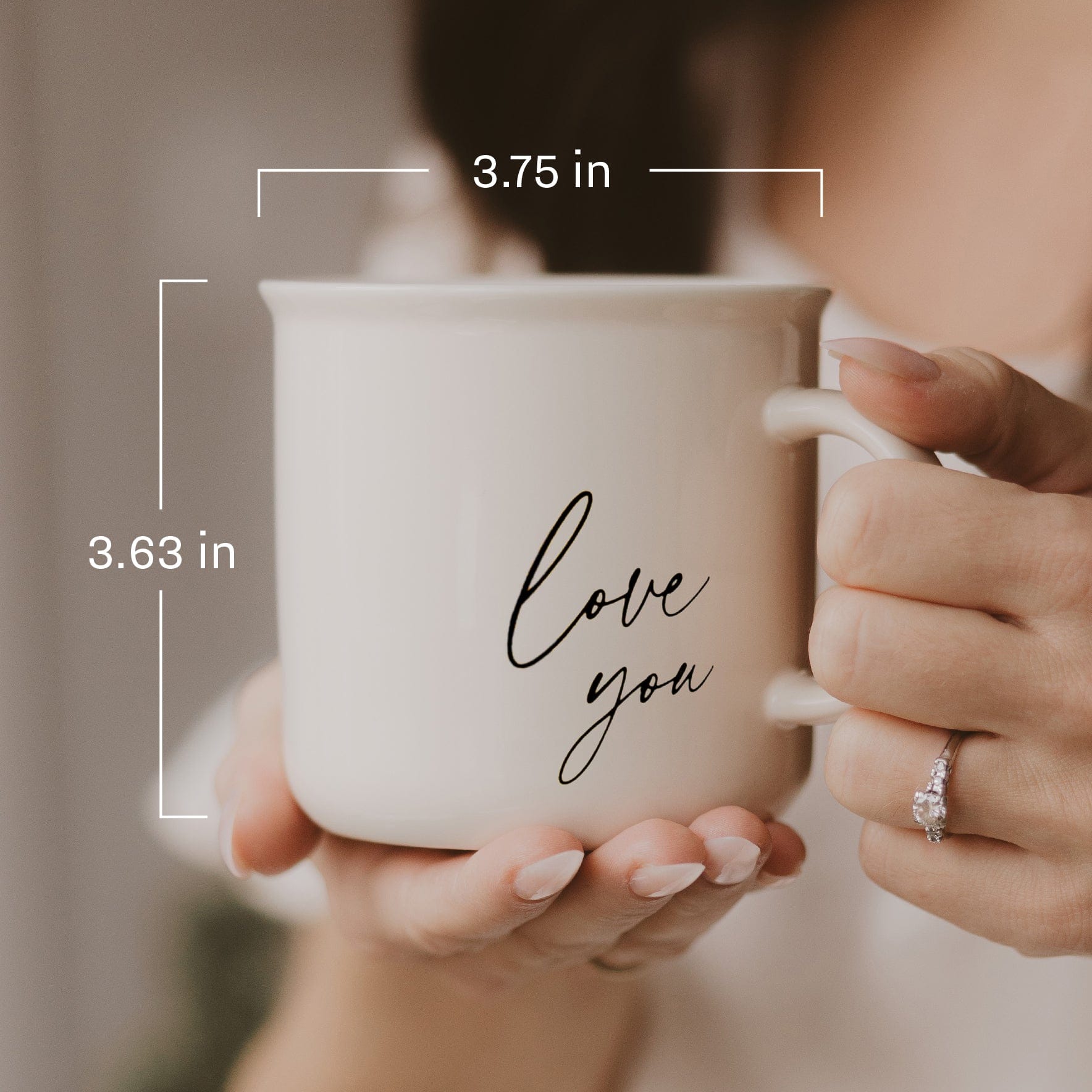 White ceramic mug with "love you" script text, held in hands showing engagement ring, with dimension measurements displayed.
