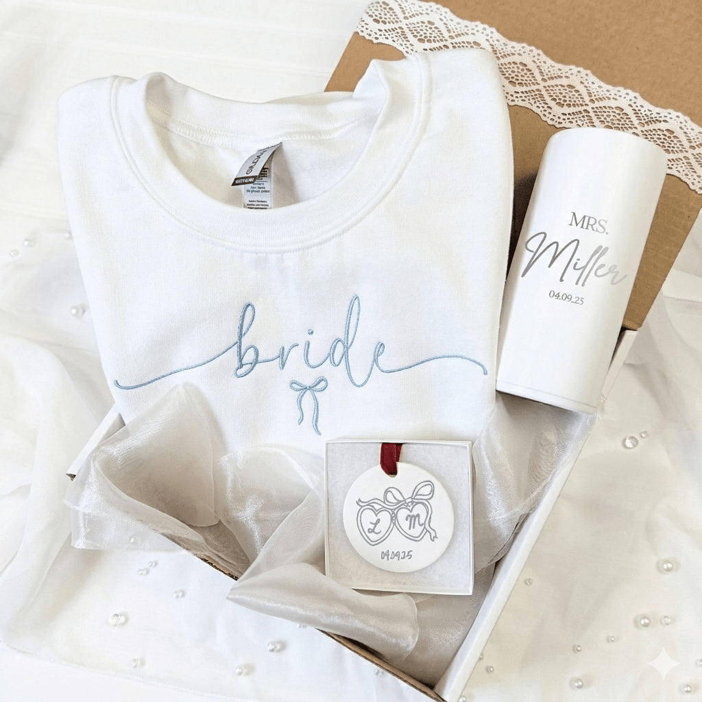 White bridal gift set with embroidered sweatshirt, custom skinny can cooler, and ornament with personalized wedding text