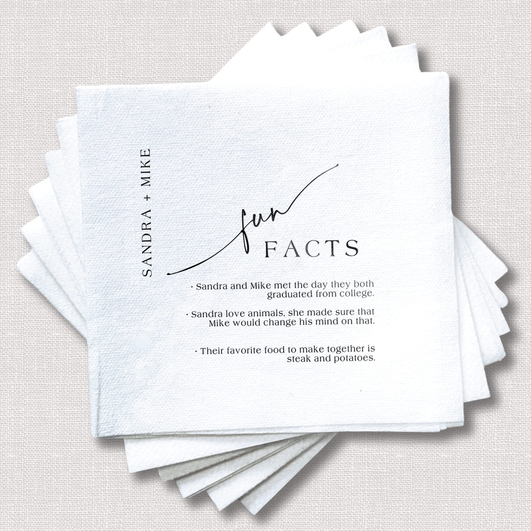 Stack of white linen napkins with "Fun Facts" header and personalized wedding details printed in black ink, including couple's names and fun facts about them.