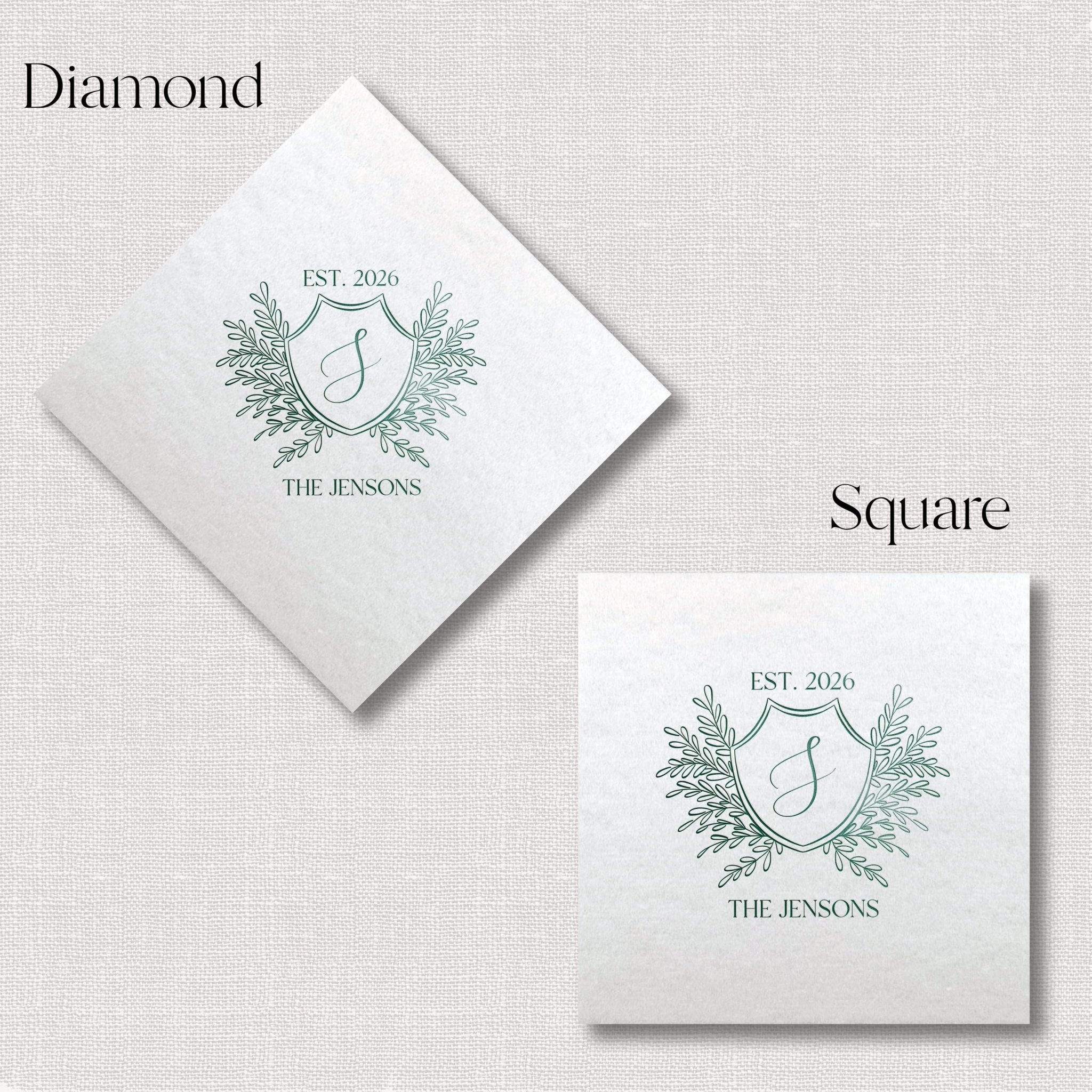 White linen napkins in diamond and square shapes featuring custom monogram crest with "EST. 2020" and "THE JENSONS" text, foil stamped design with leafy flourishes.