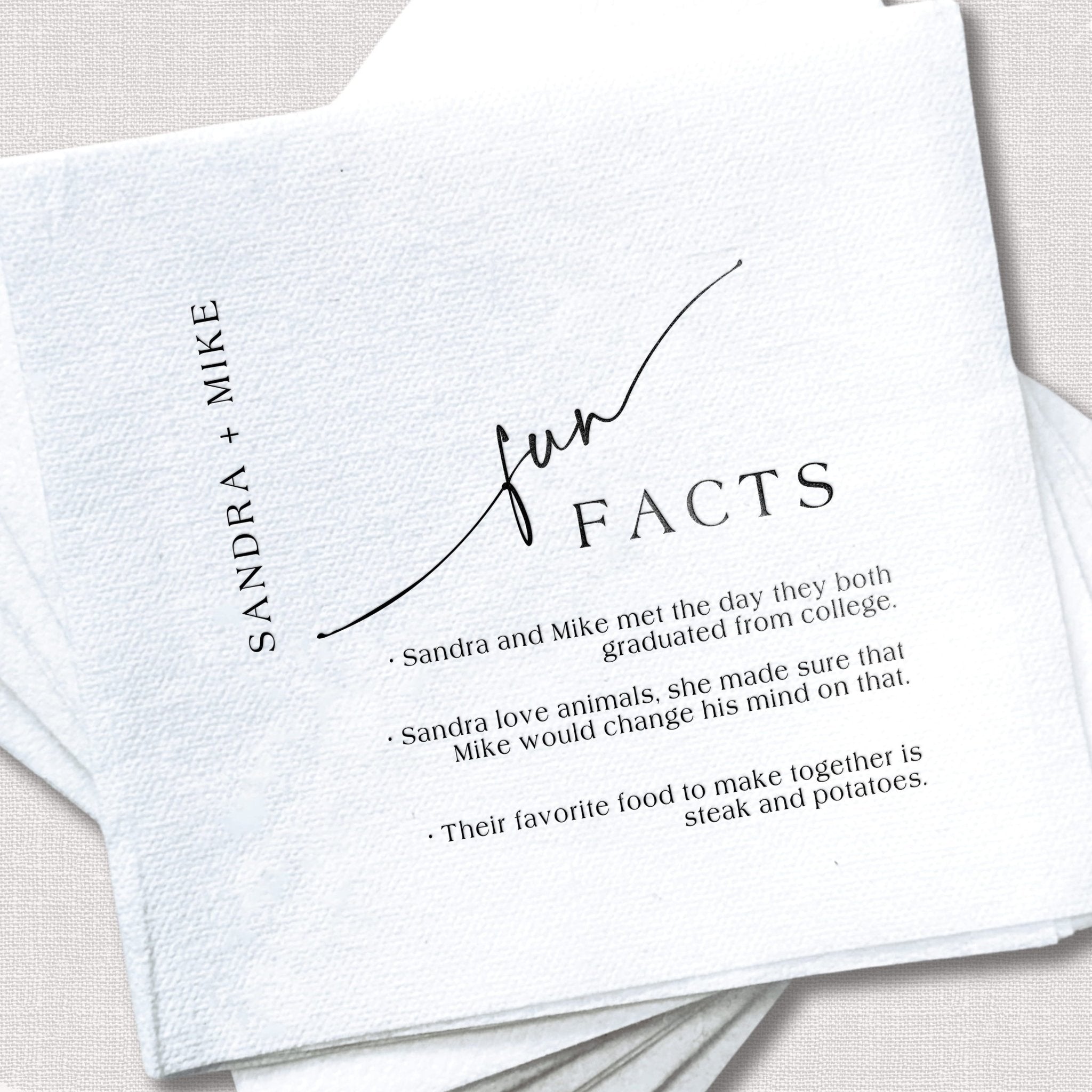 White linen napkin with "Our Facts" header and personalized couple names Sandra and Mike, listing fun facts about how they met and their favorite activities.