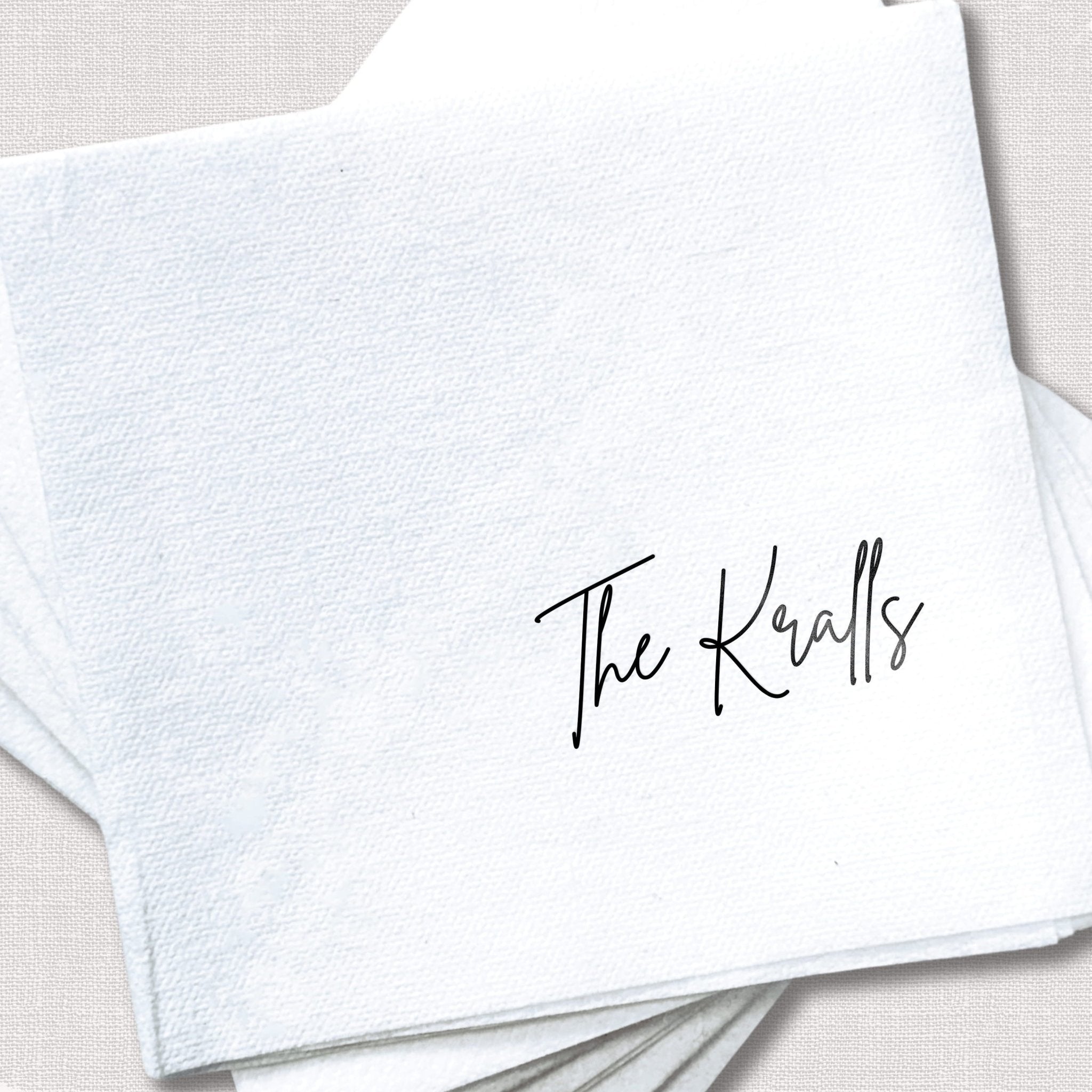 White linen napkin with "The Knatls" printed in black script lettering