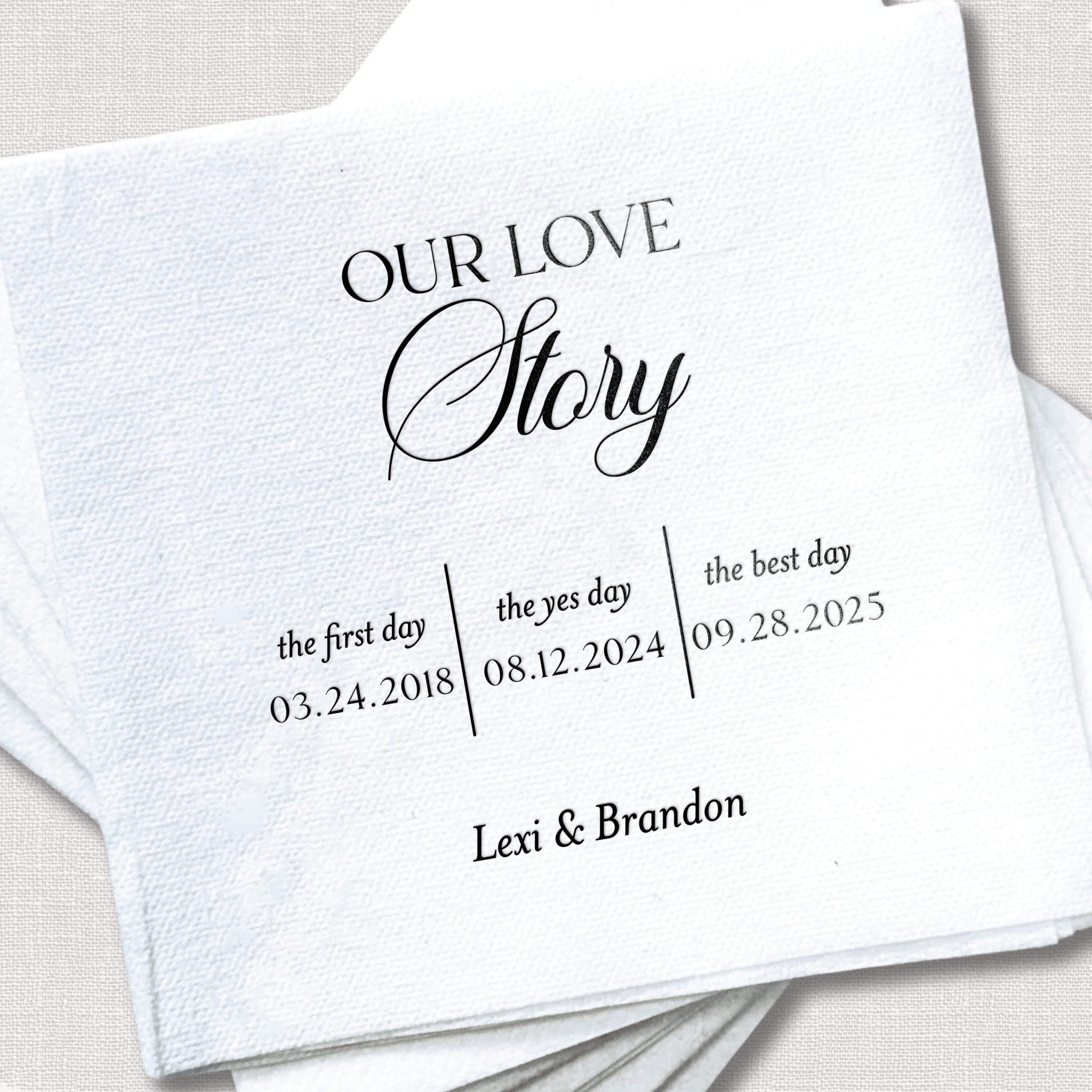 White linen napkin with "Our Love Story" text and three dates: first day 03.24.2018, they yes day 08.12.2024, best day 09.28.2023, personalized with names Lexi & Brandon