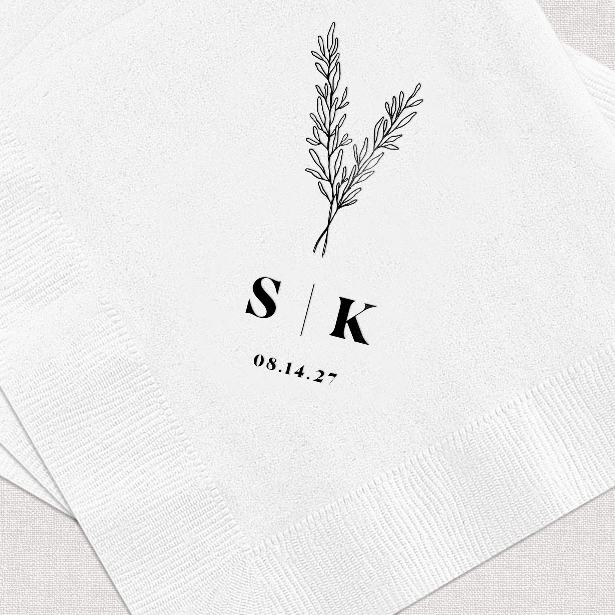 White napkin with initials S and K, botanical line drawing, and wedding date 08.14.23 in black foil stamping