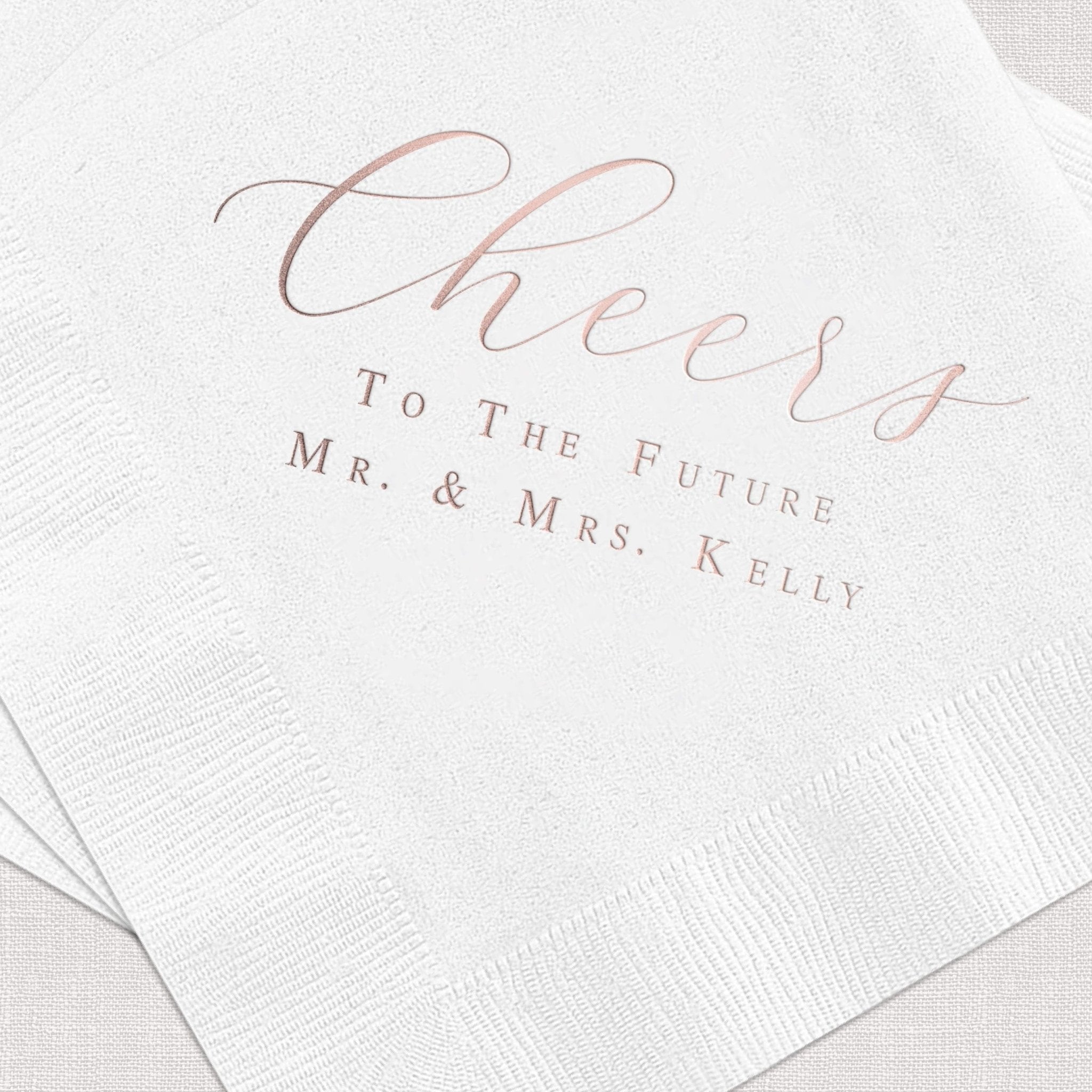 White napkin with rose gold foil stamped text reading "Cheers to the Future Mr. & Mrs. Kelly"