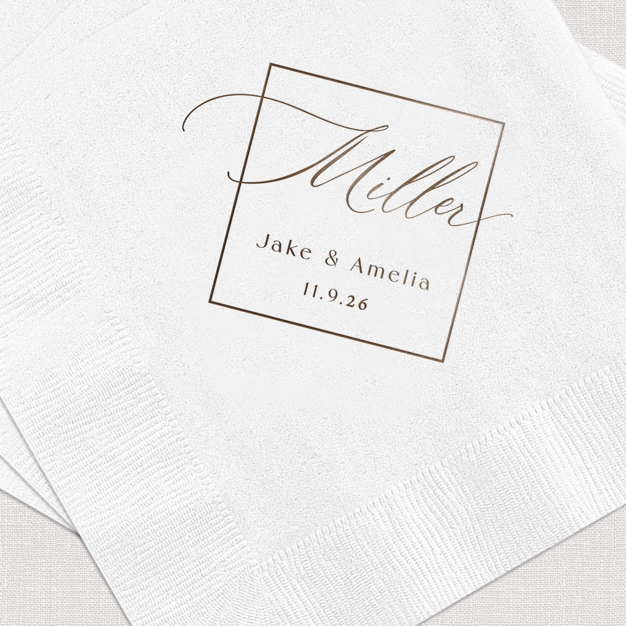 White foil-stamped napkins with "hello" script and "Jake & Amelia 11.9.26" in gold lettering inside a square frame