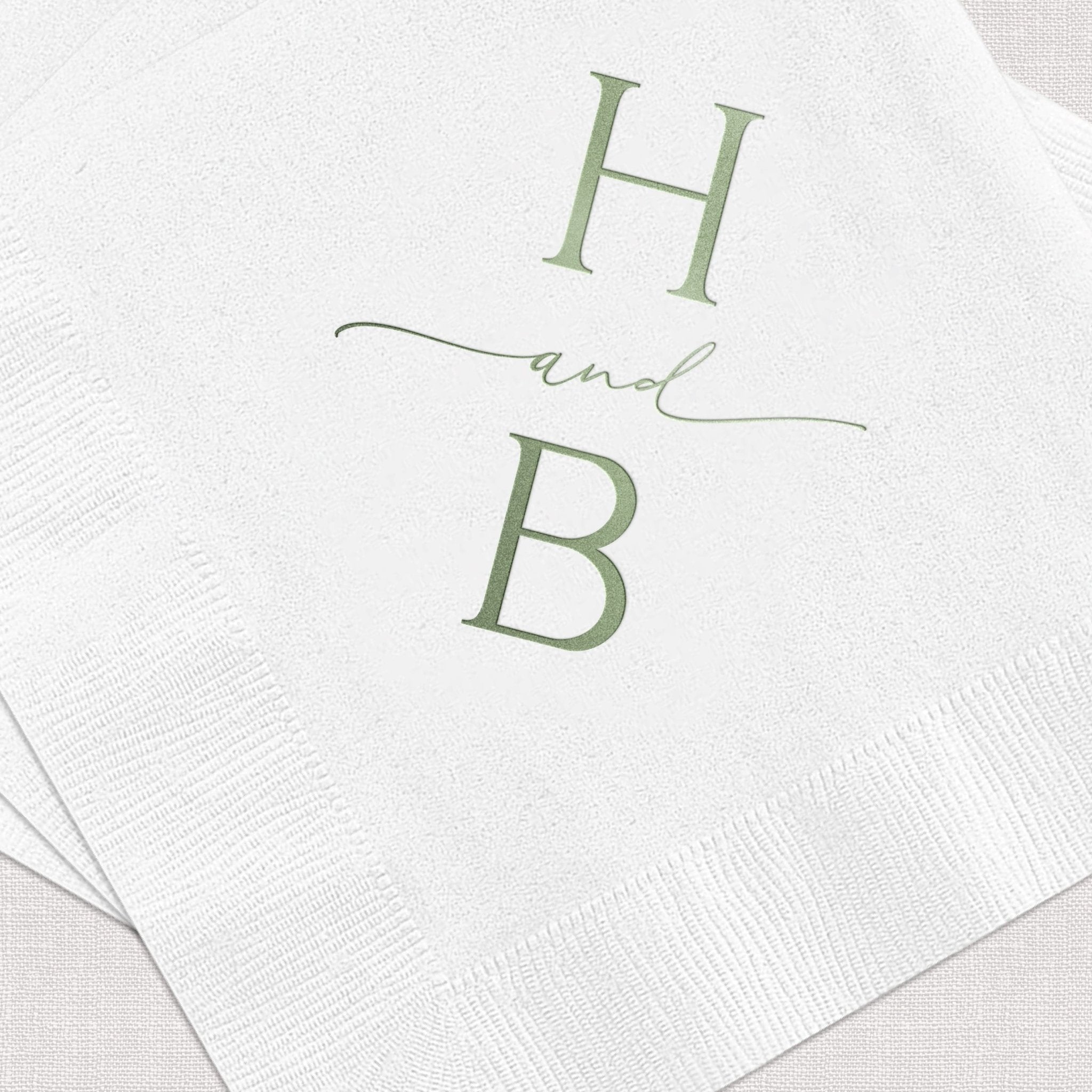 White paper napkins with sage green foil stamped monogram design featuring H and B letters with "and" script between them.