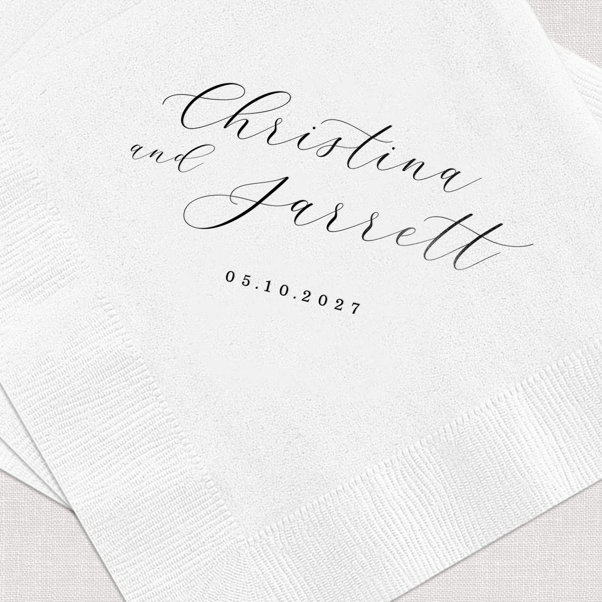 White cocktail napkins with elegant script names "Christina Faisetti" and date 05.10.2027 in foil stamping