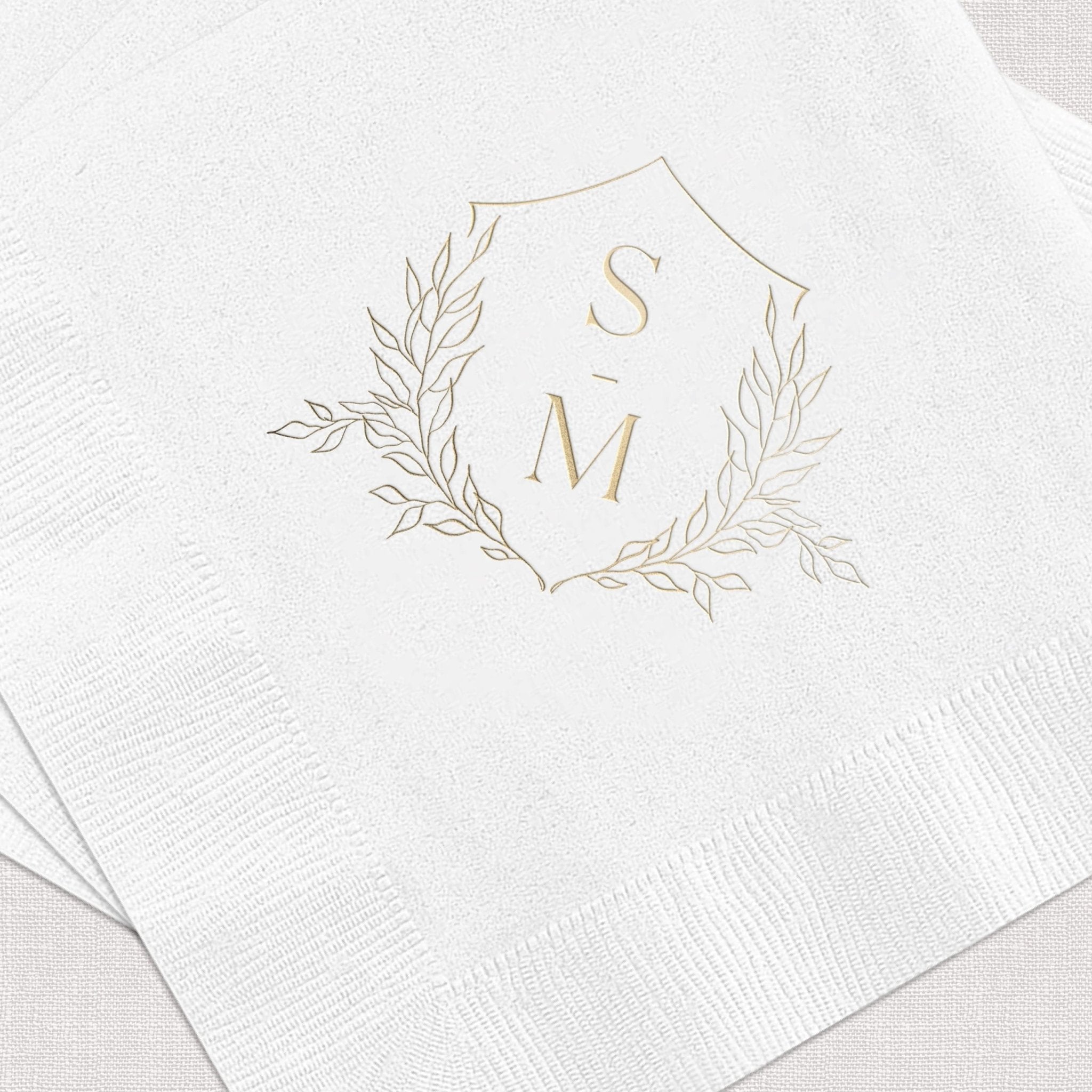 White cocktail napkins with gold foil monogram SM surrounded by delicate leaf wreath design