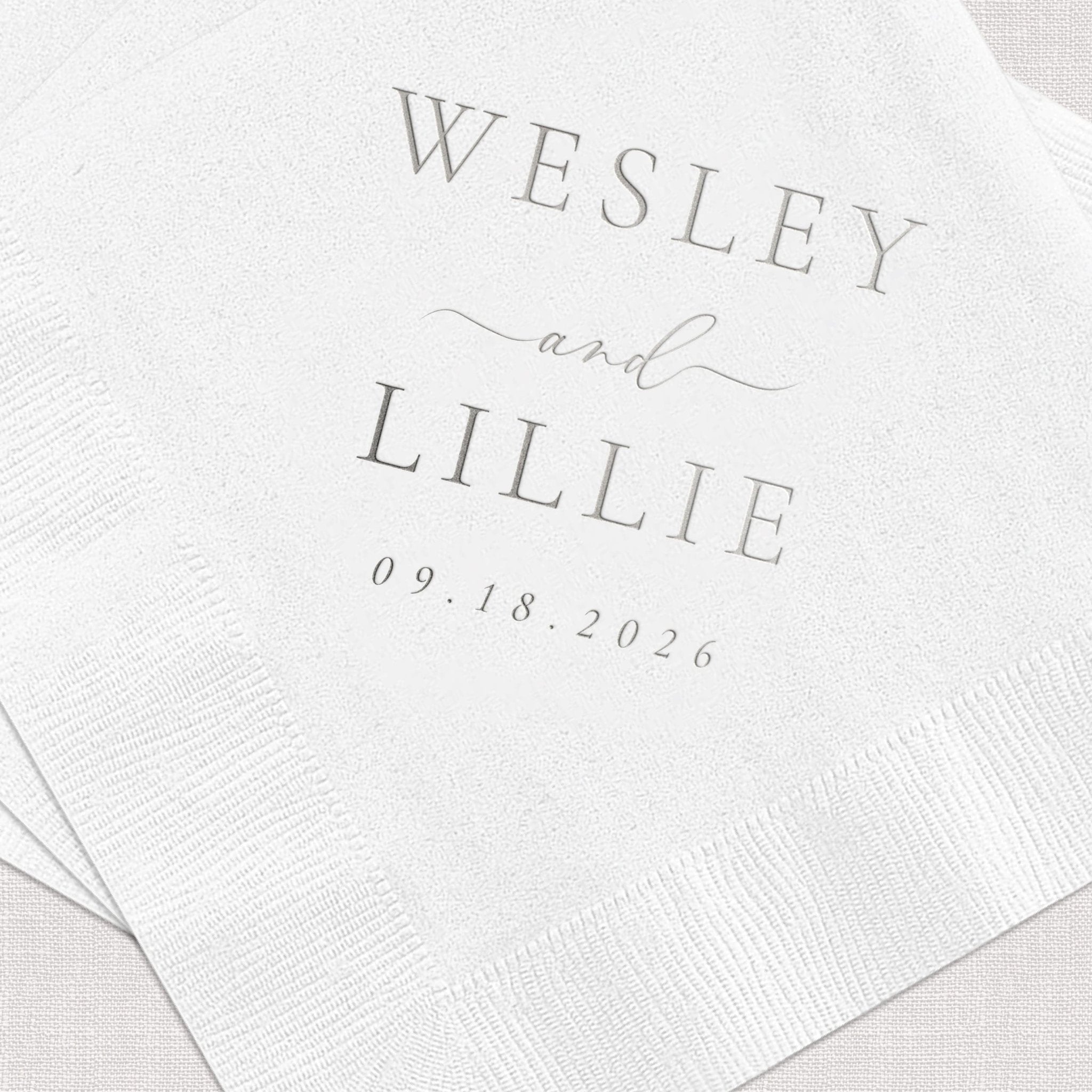 White napkins with gray foil stamped text reading "Wesley and Lillie" with wedding date 09.18.2026