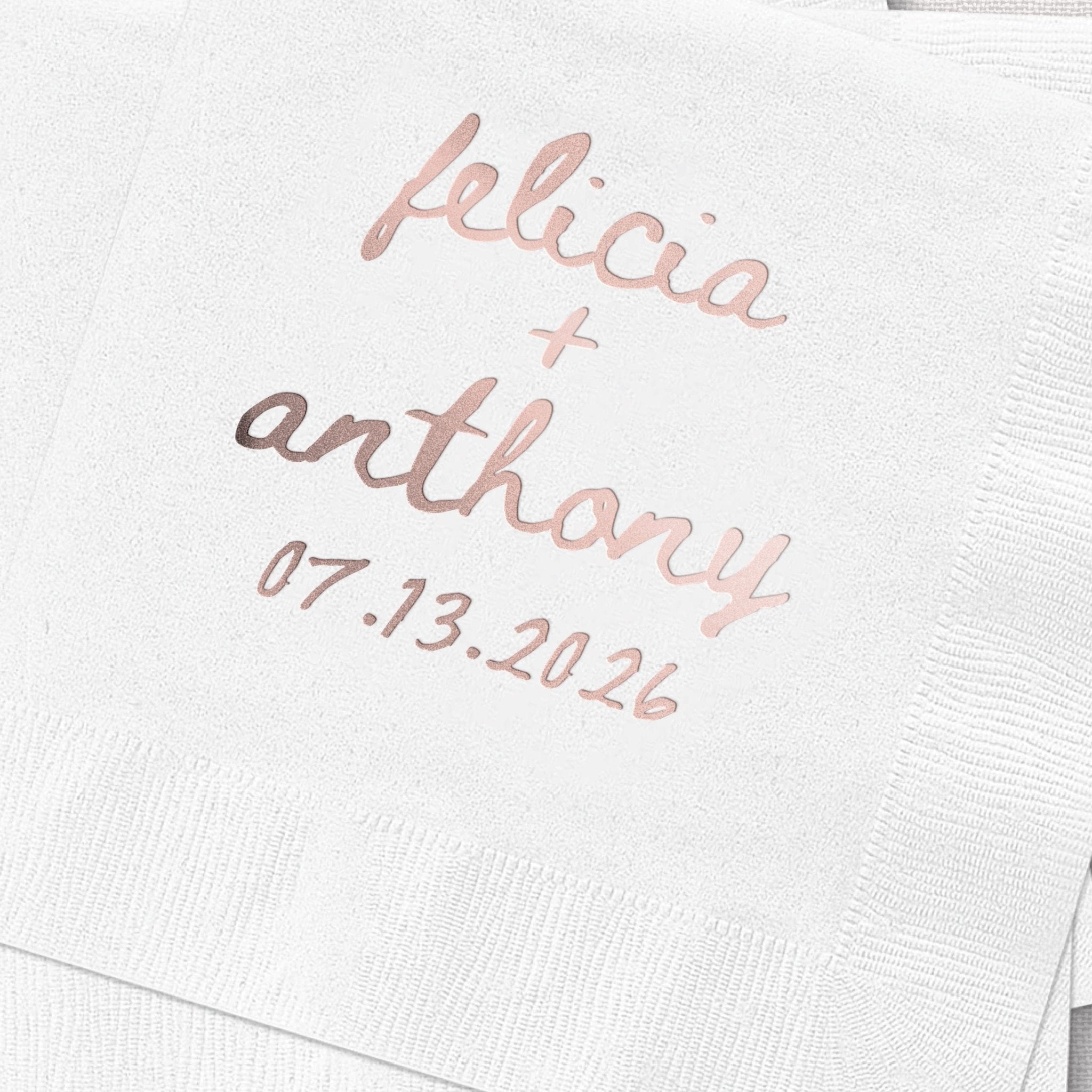 White cocktail napkin with rose gold foil stamped names "felicia + anthony" and wedding date 07.13.2026