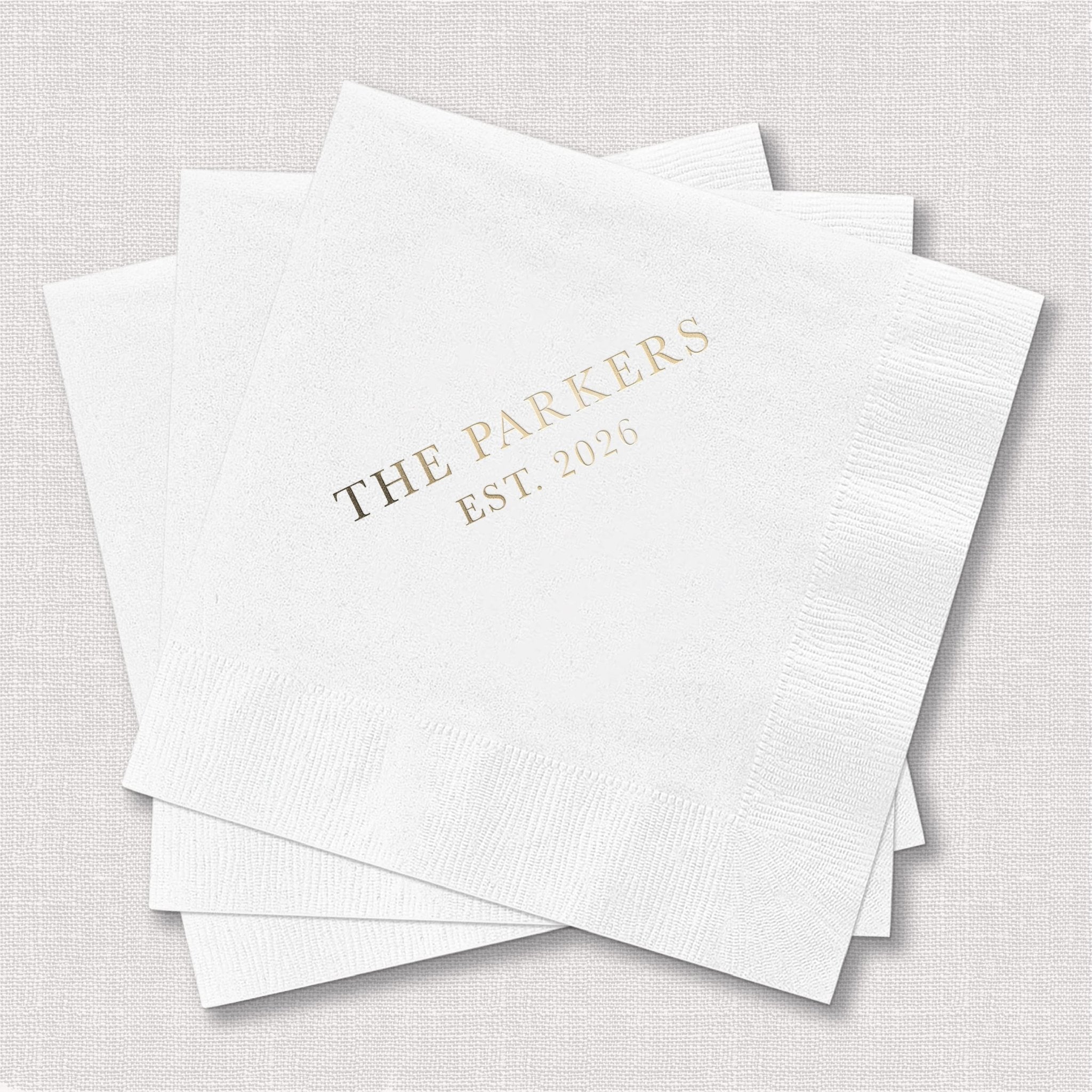 Stack of white cocktail napkins with gold foil text reading "THE PARKERS EST 2024"