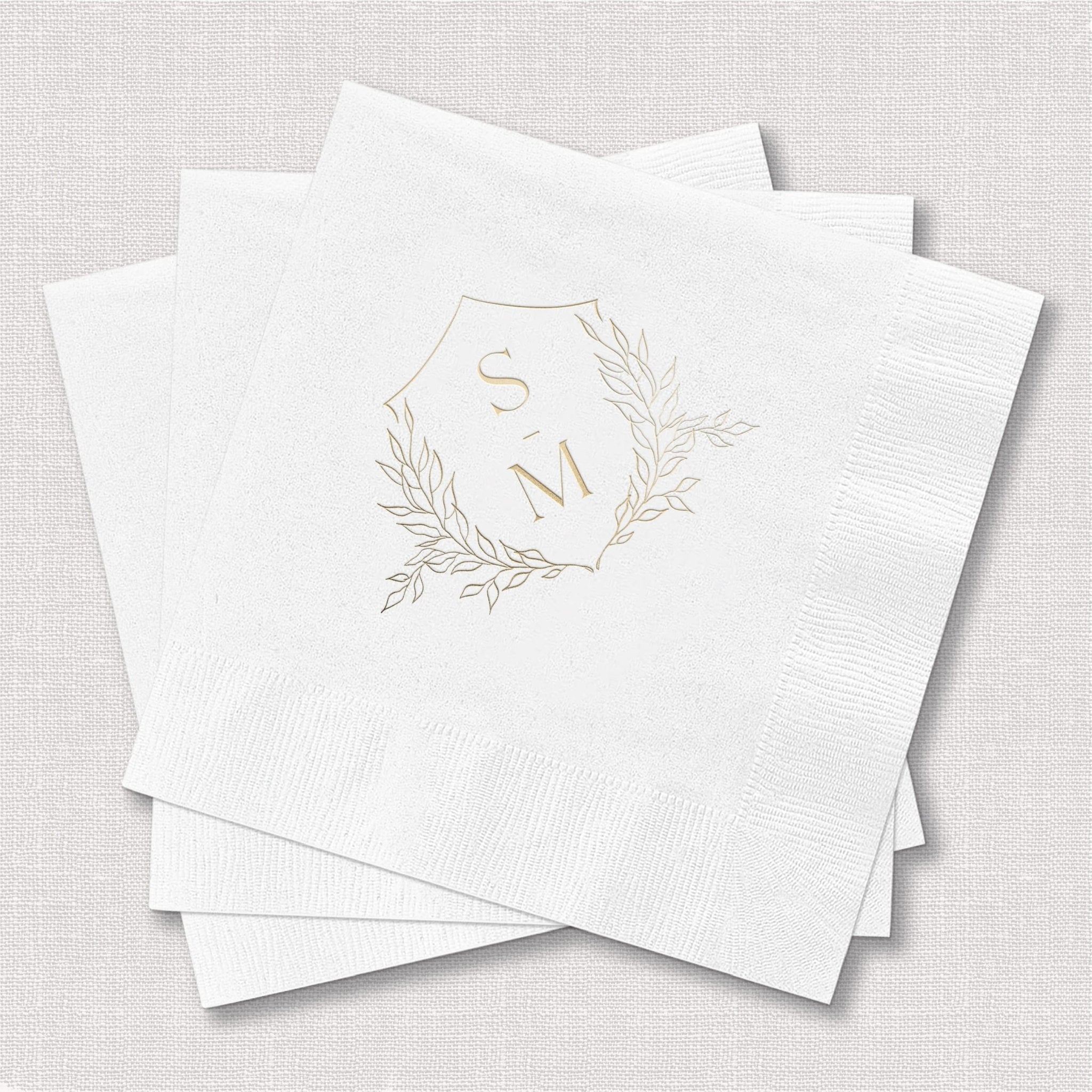 Stack of white napkins with gold foil monogram wreath design and initials S and M.