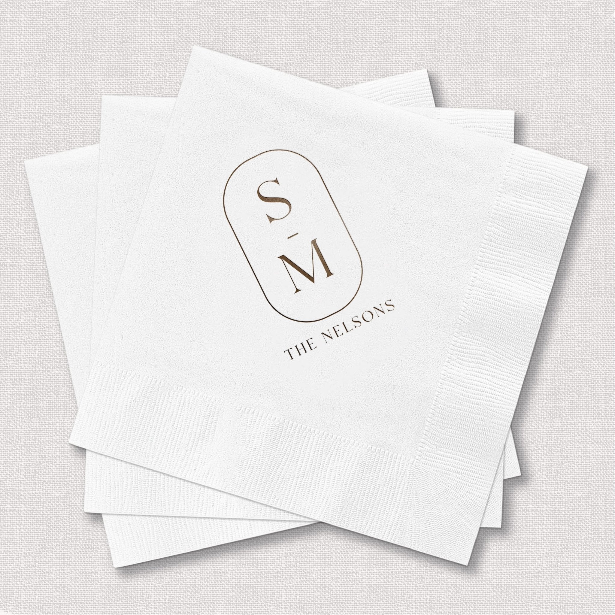 Stack of white foil-stamped napkins with initials S and M in oval monogram and "The Seasons" text below.