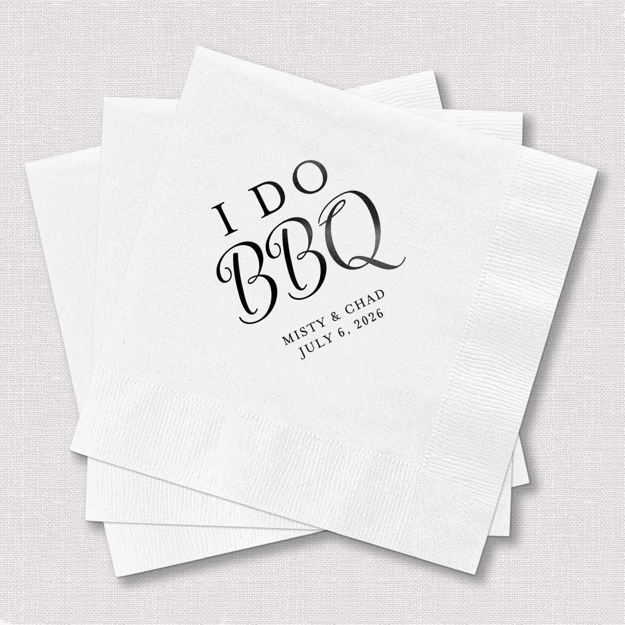 White napkins with "I Do BBQ" text and personalized names and date in black foil stamping, stacked together.