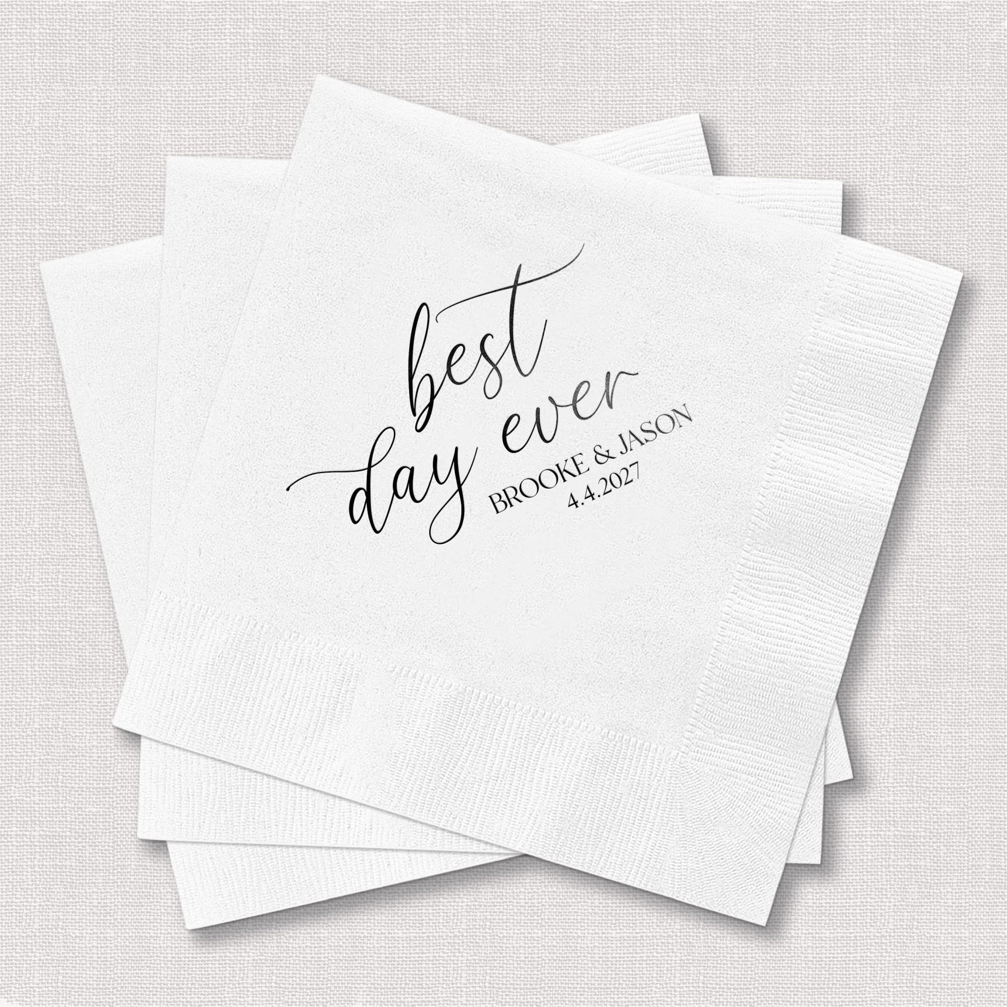Stack of white napkins with "best day ever" in script and personalized names and date in smaller text