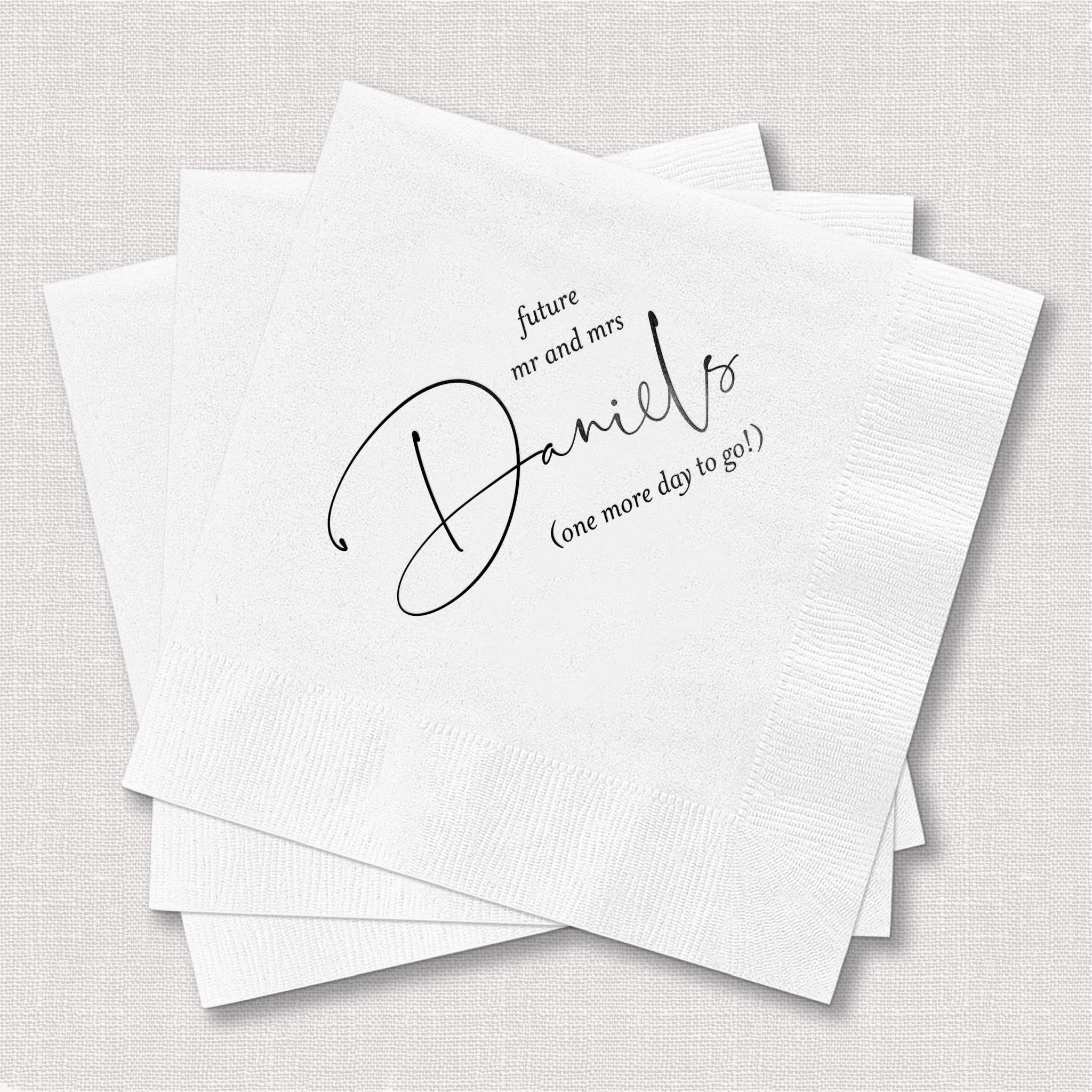 White napkins with black foil-stamped script reading "Daniels" and "forever and always, one more day to go"