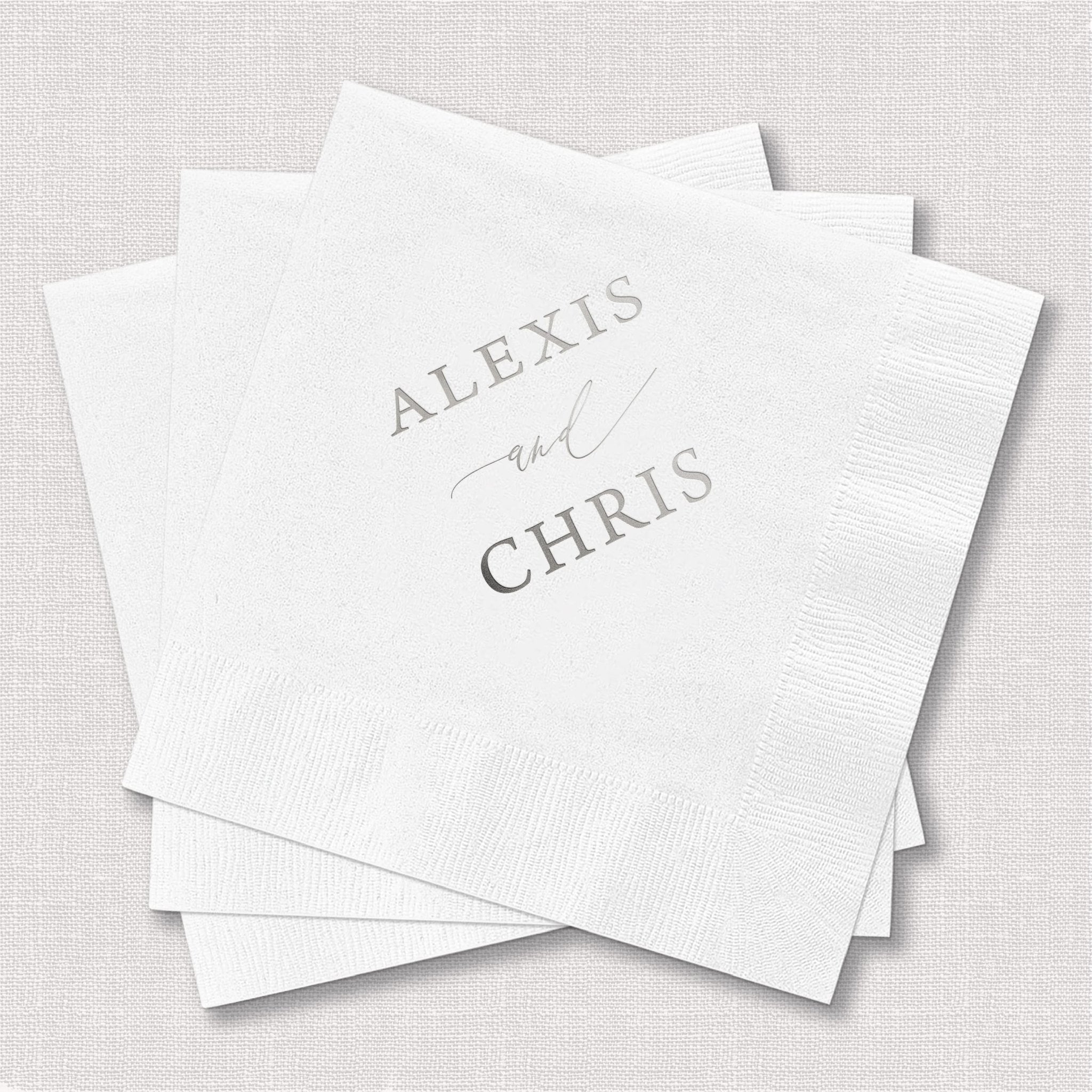 Stack of white cocktail napkins with "Alexis and Chris" personalized in gray foil lettering