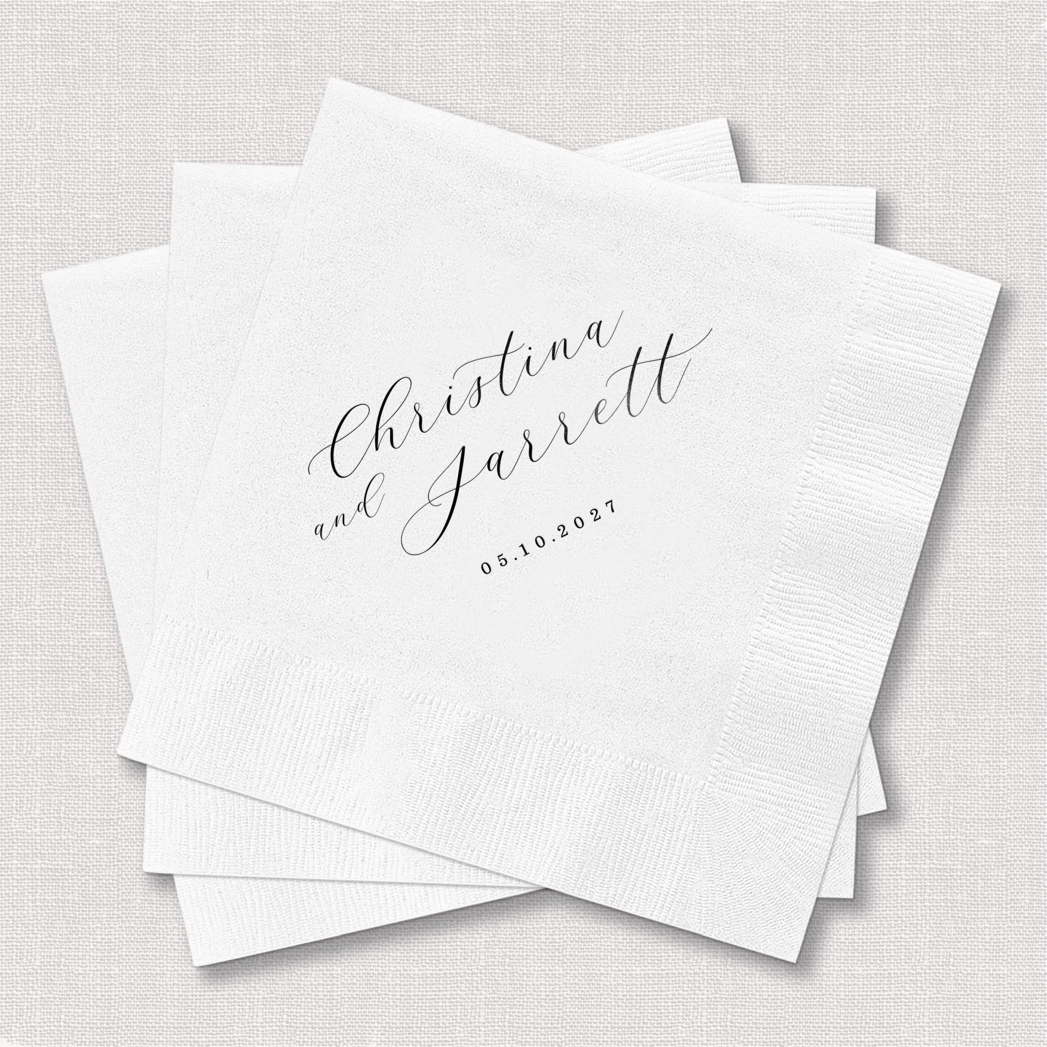 White cocktail napkins with "Christina and Jarrett" in script and date 08.10.2024 in gray foil stamping