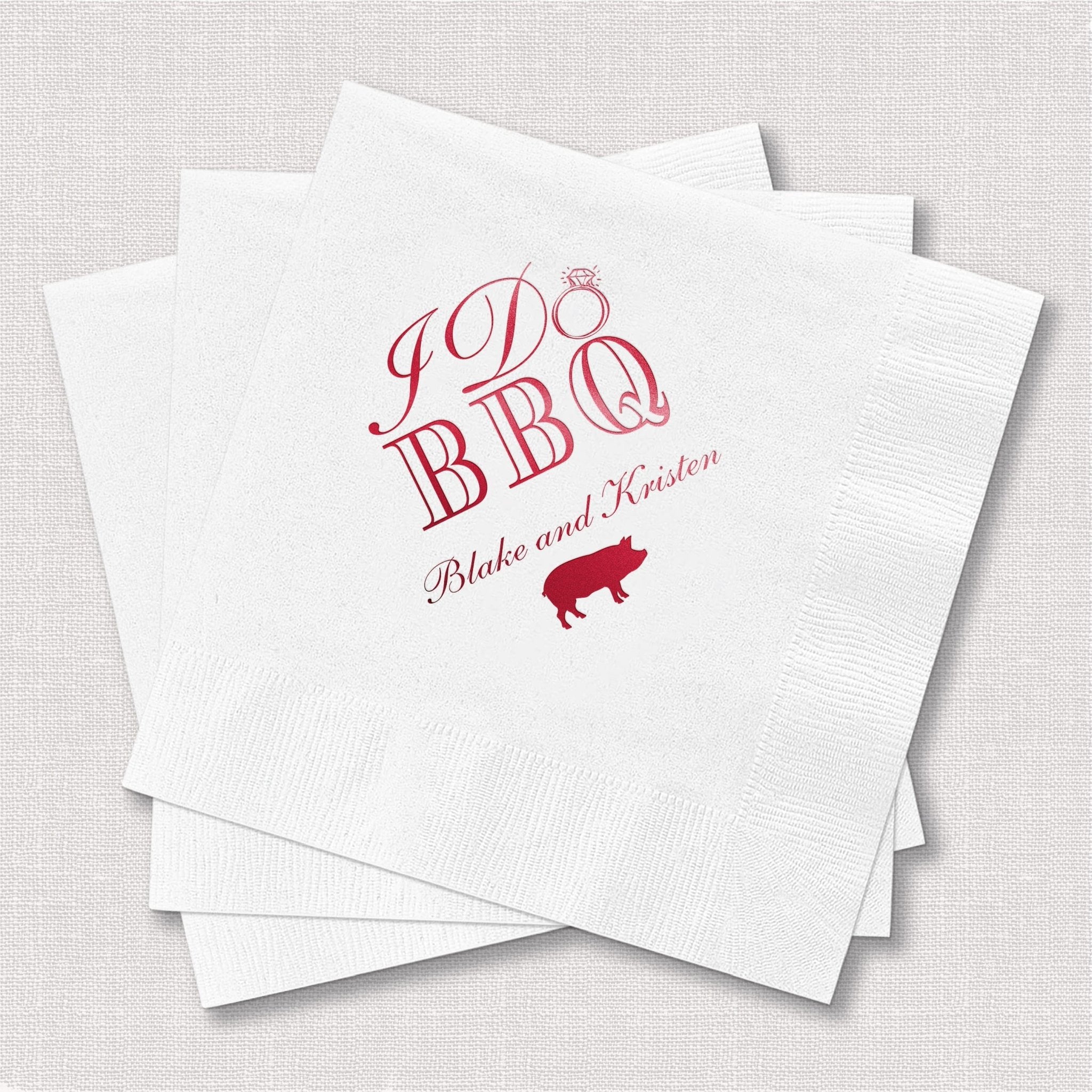 White napkins with pink foil-stamped I Do BBQ design, pig icon, and personalized names Blake and Kirsten