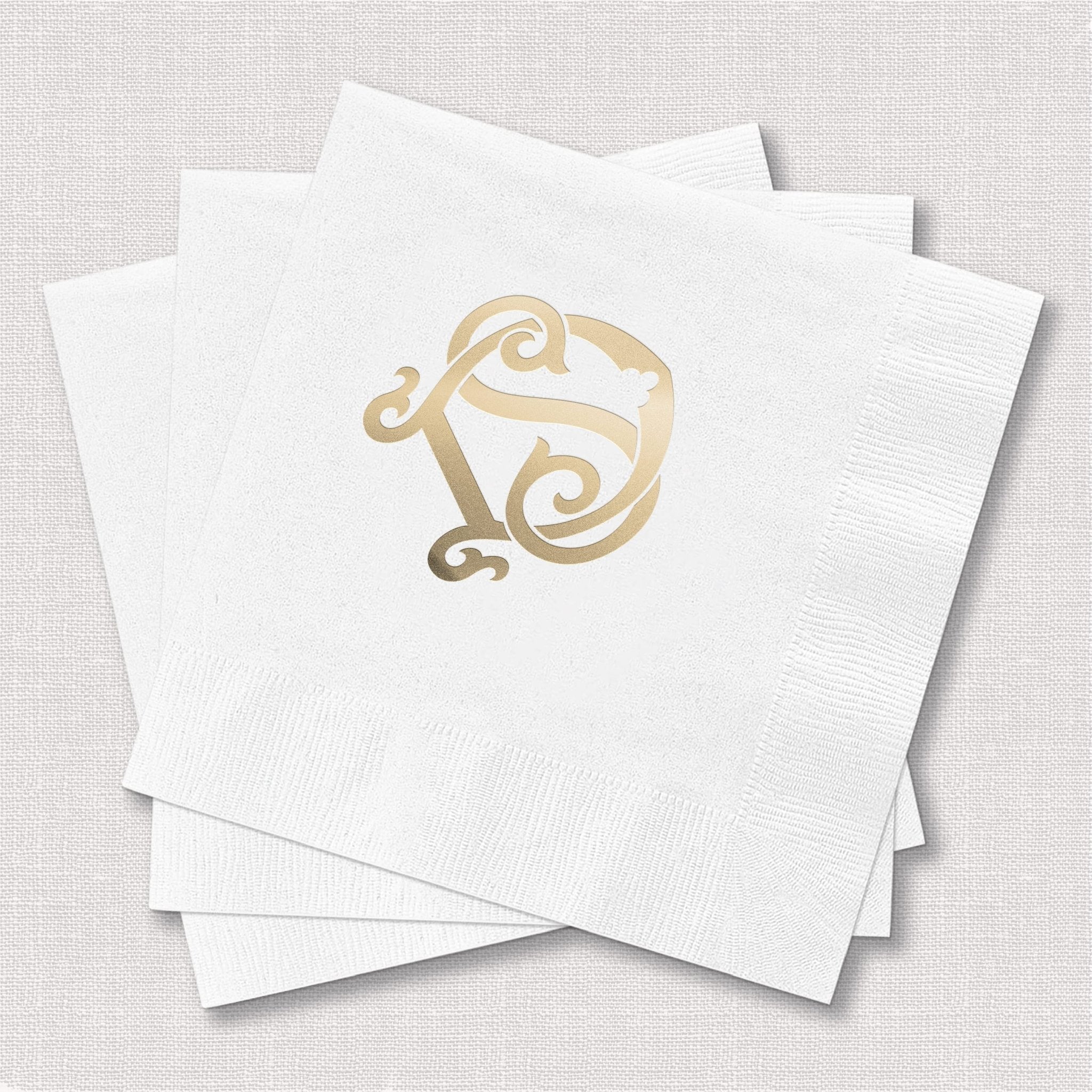 White napkins with gold foil monogram design in elegant script lettering