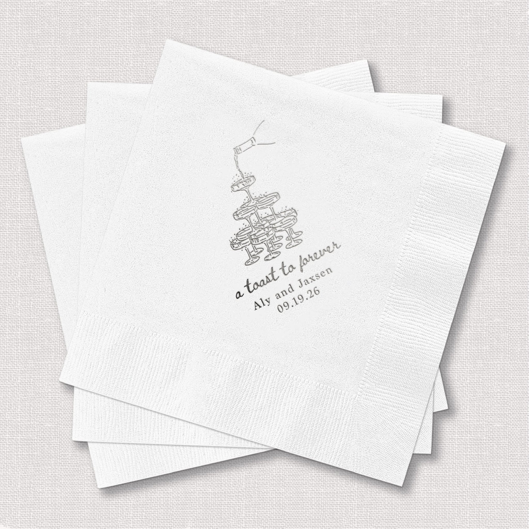 White cocktail napkins with silver foil stamped mistletoe design and "A toast to forever" text with wedding date personalization