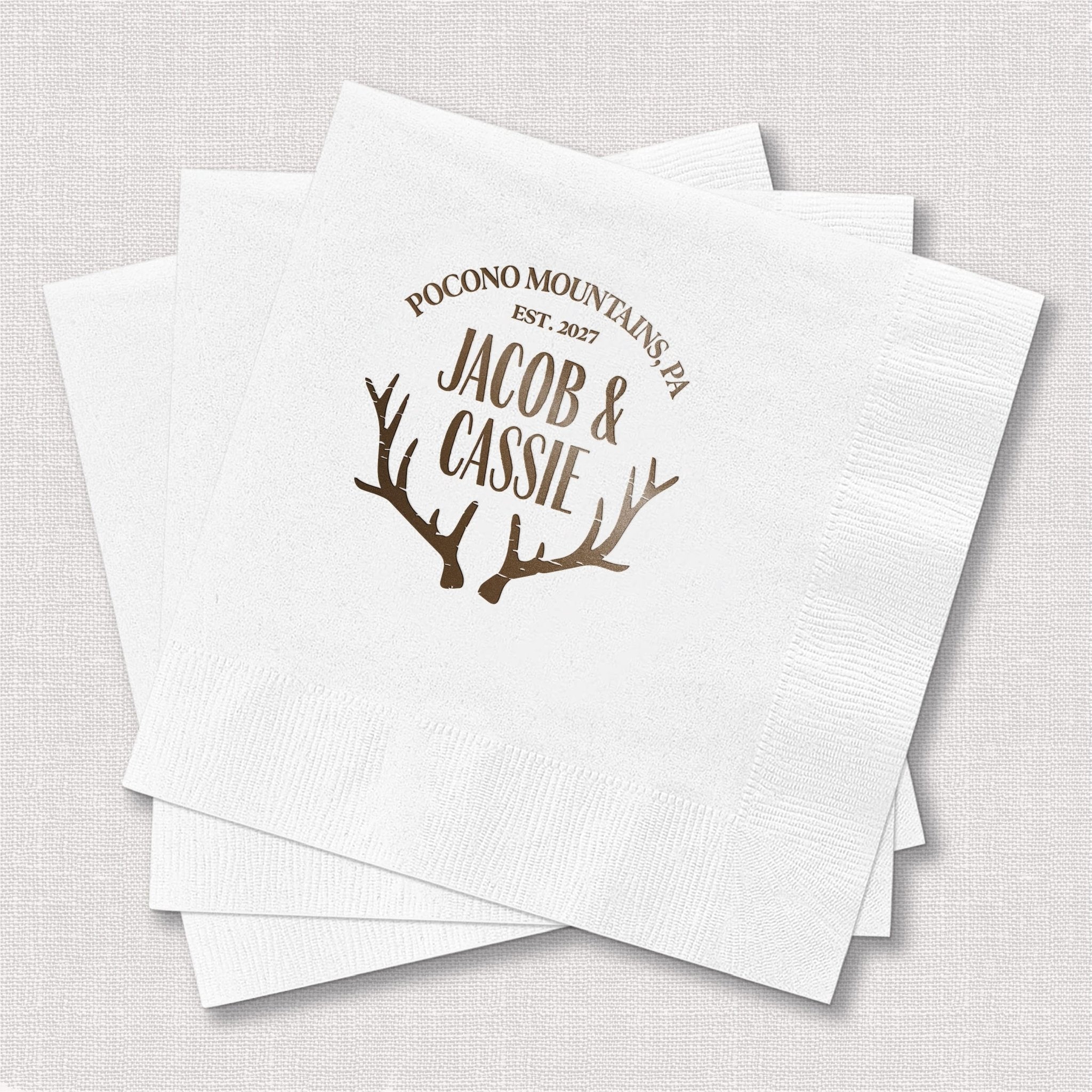 White foil-stamped napkins with antler design and personalized names Jacob and Cassie with Pocono Mountains wedding date