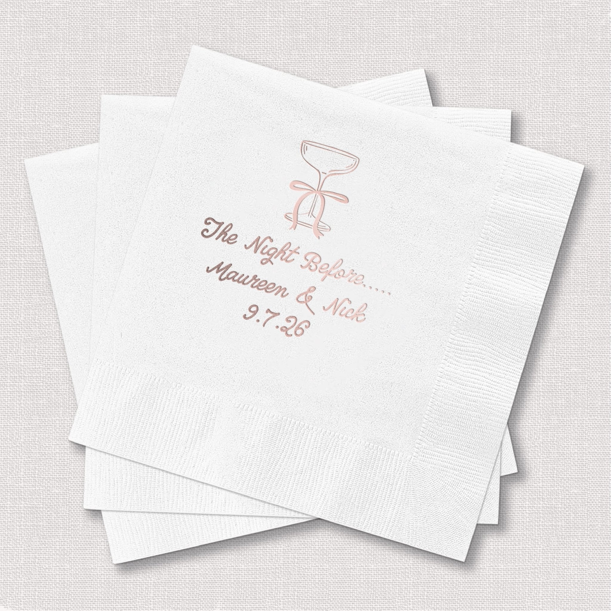White cocktail napkins with rose gold foil stamped design featuring martini glass and personalized wedding rehearsal dinner text.