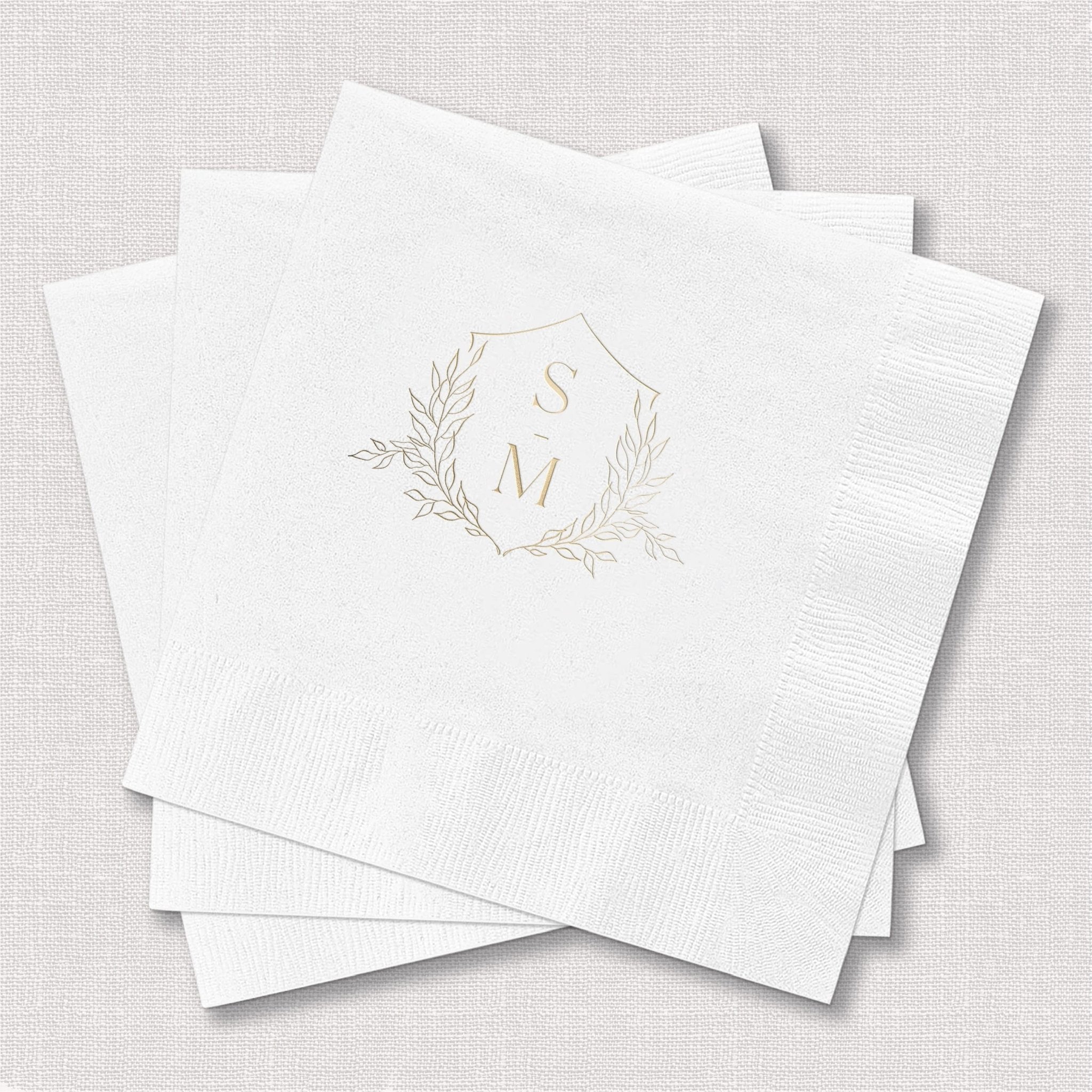 White foil-stamped napkins with gold monogram initials S and N surrounded by delicate leaf wreath design