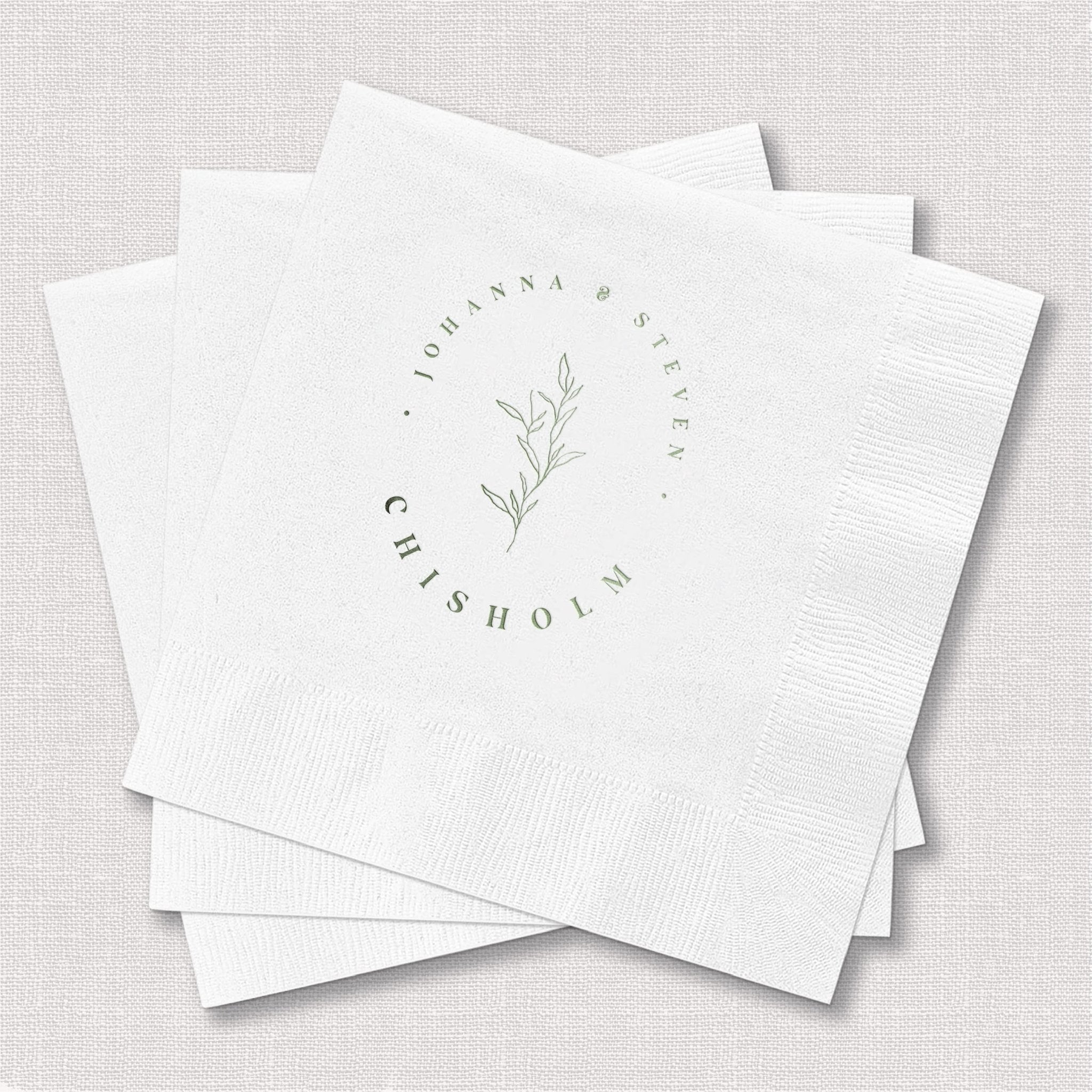 Stack of white foil-stamped napkins with botanical leaf design and personalized circular text reading "Johanna & Ryan" and "his holm"