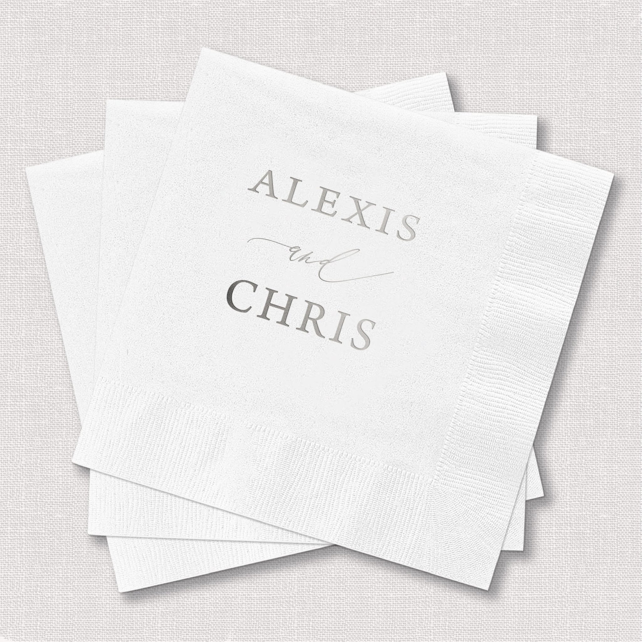 Stack of white cocktail napkins personalized with "Alexis" and "Chris" in gray foil lettering