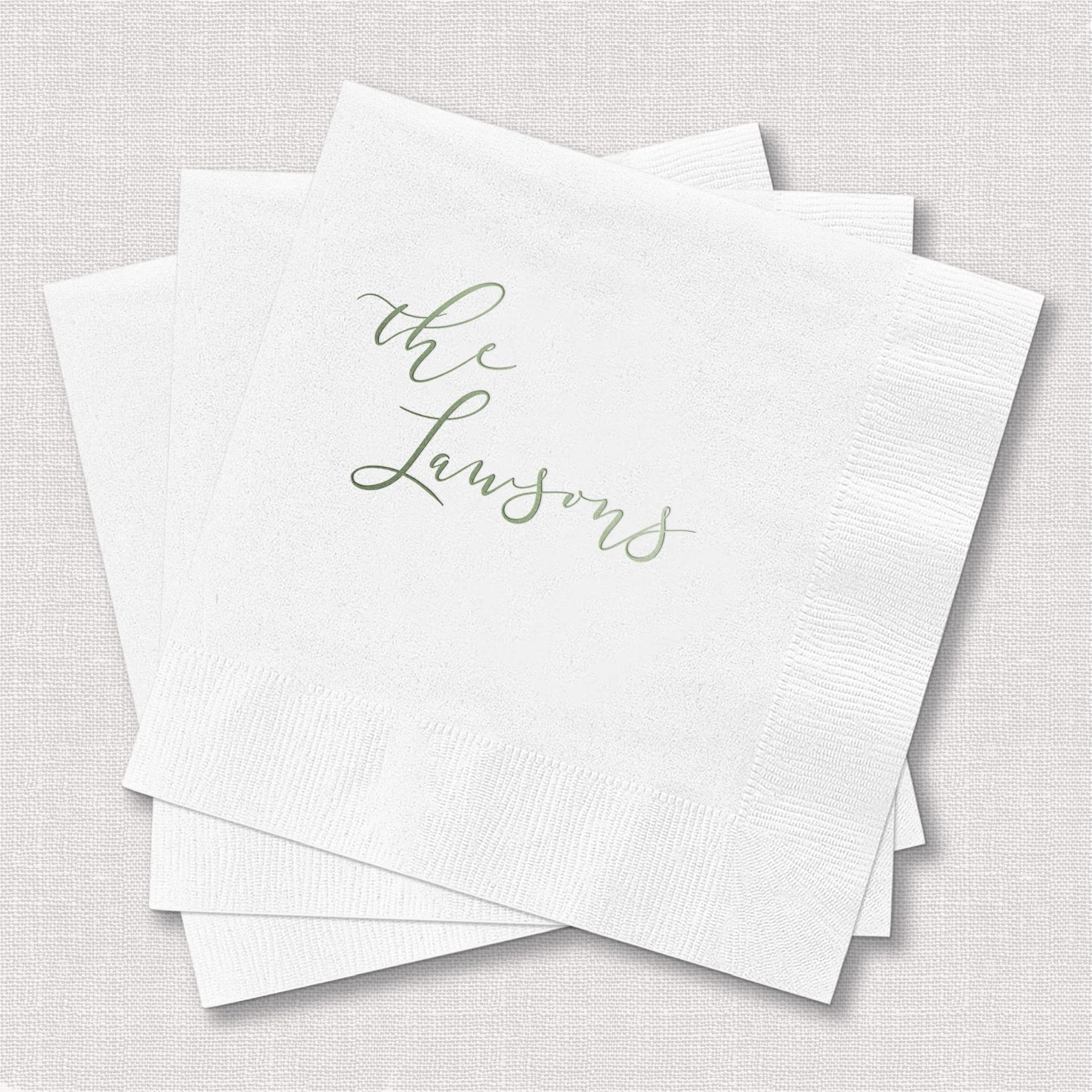 Stack of white cocktail napkins with "the Lawsons" in gold script lettering.