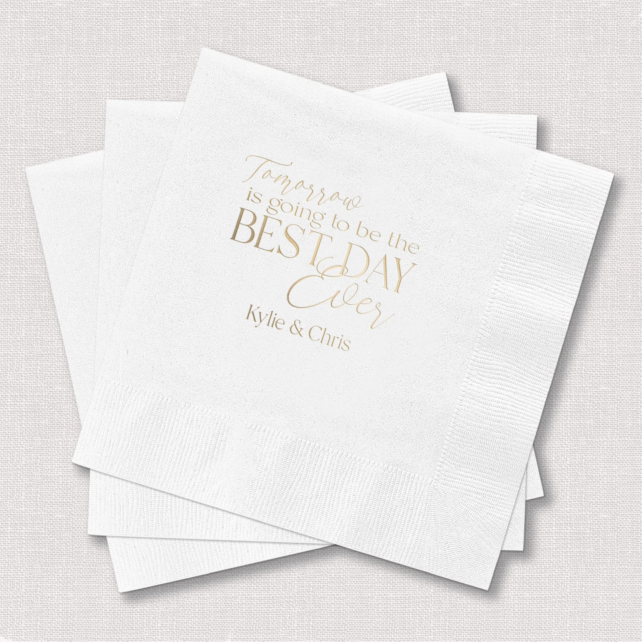 Stack of white cocktail napkins with gold foil text reading "Tomorrow is going to be the BEST DAY" and "Kylie & Chris"