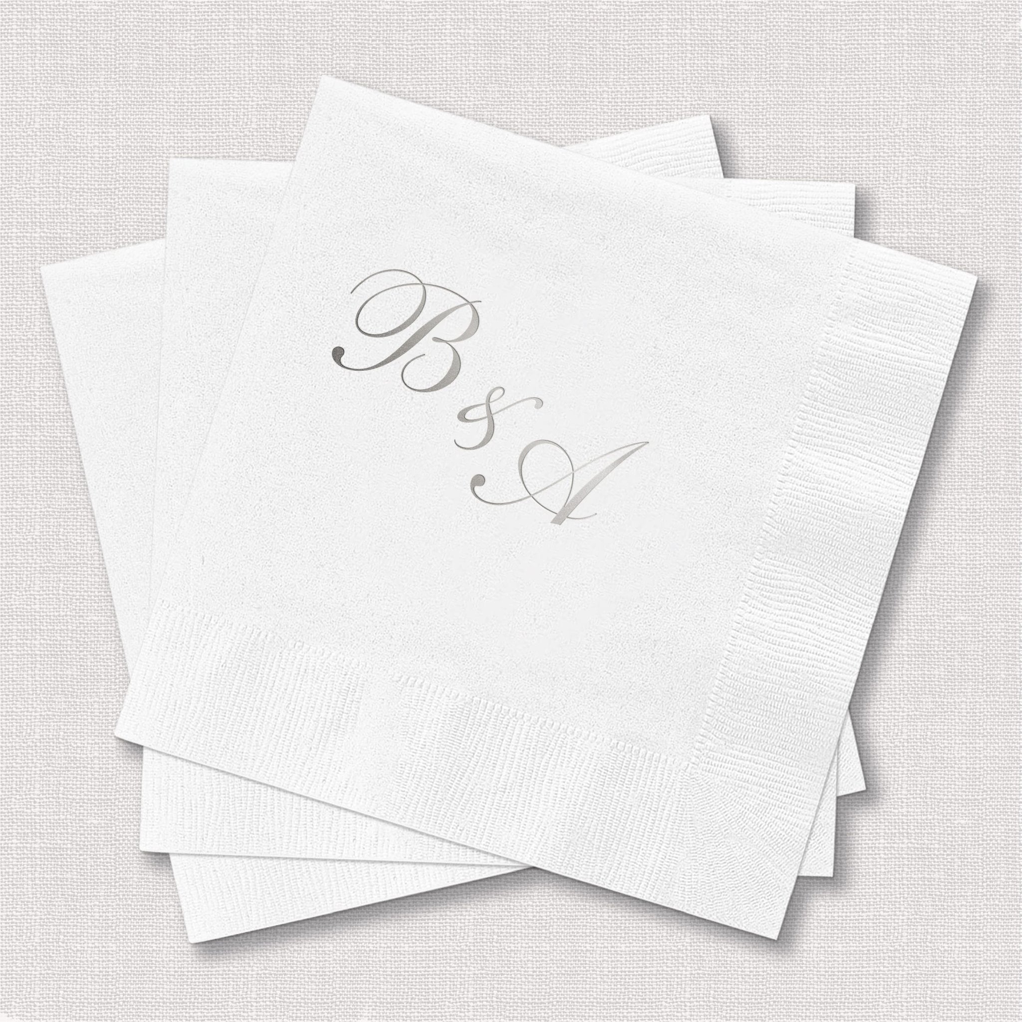 Stack of white napkins with silver foil monogram initials BSQ printed on corner