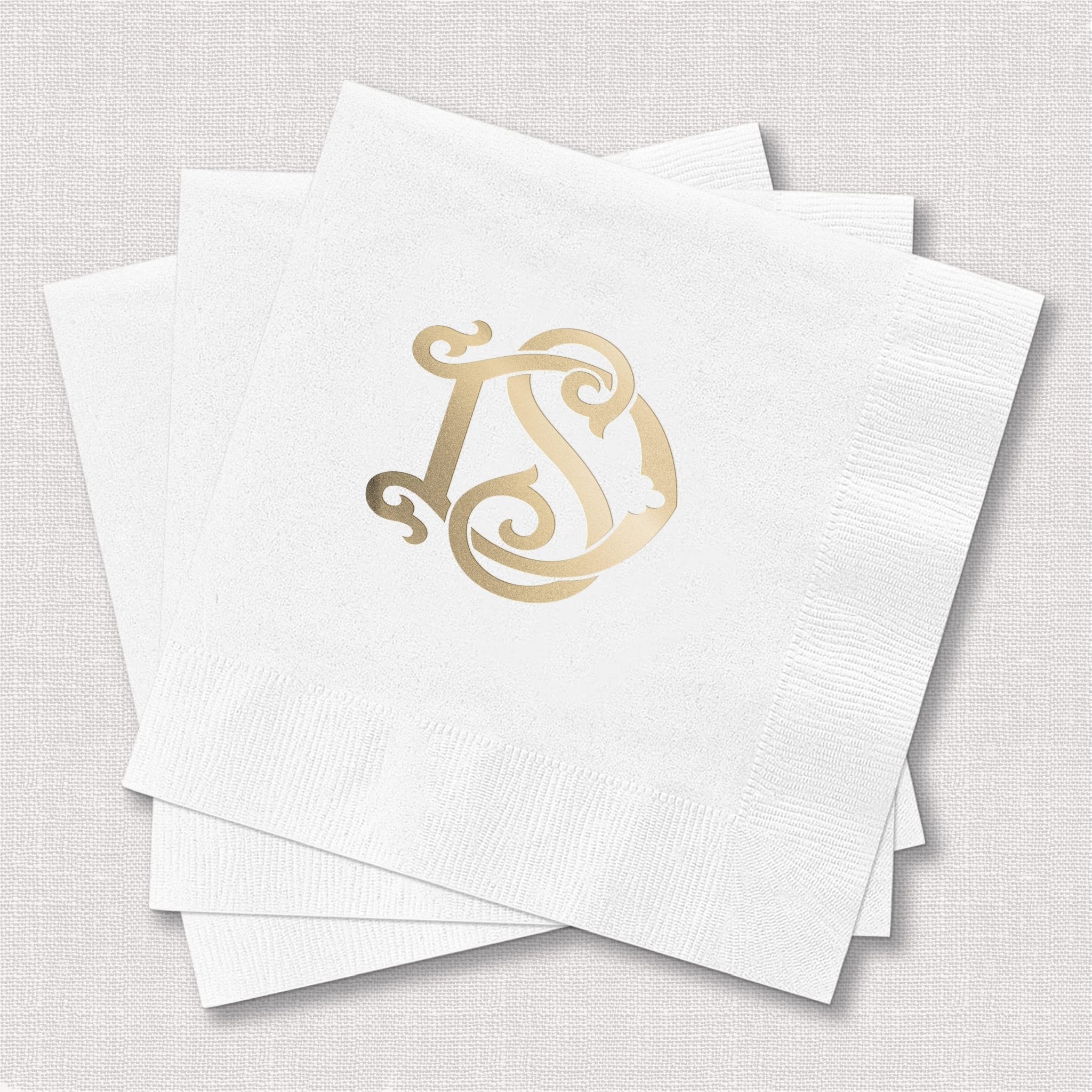 White cocktail napkins with gold foil monogram initial design, stacked display