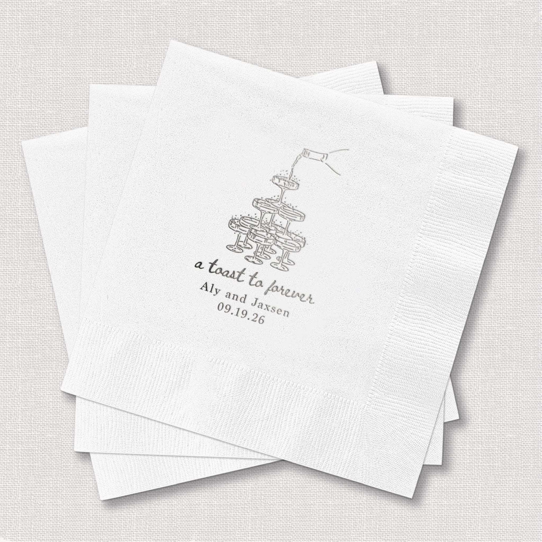 White foil stamped napkins with champagne glasses design and "a toast to forever" text personalized with names and date