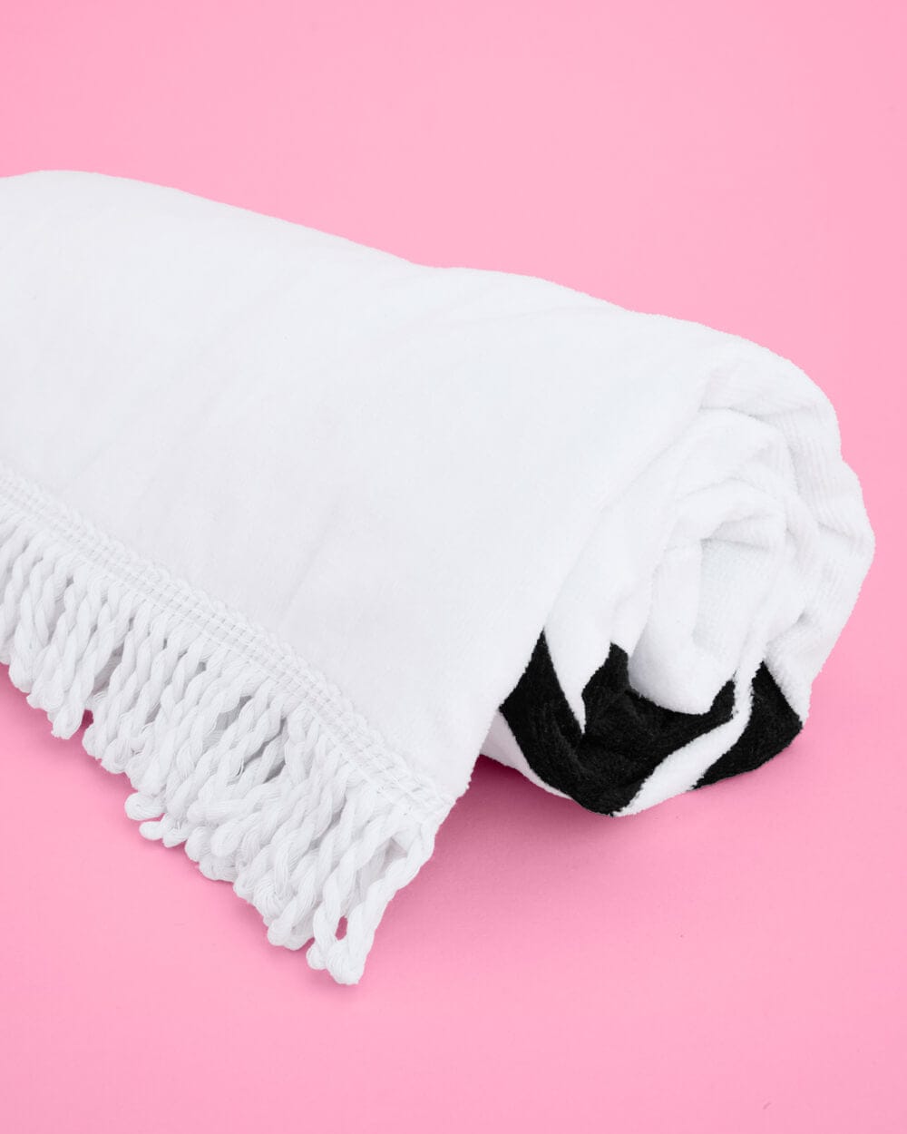 White cotton beach towel with fringe trim and black bride text design on pink background