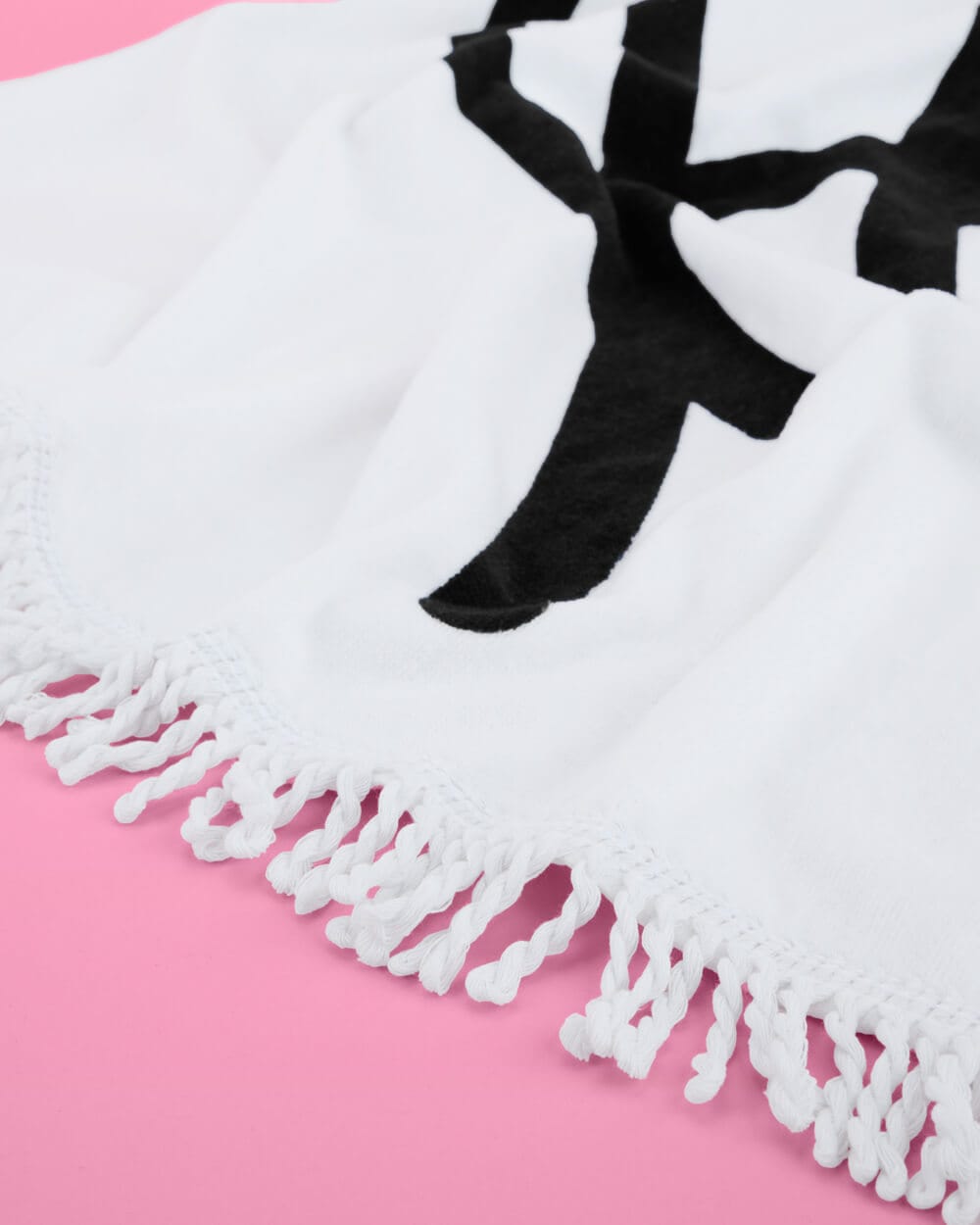 White cotton beach towel with black bride silhouette and fringe trim on pink background