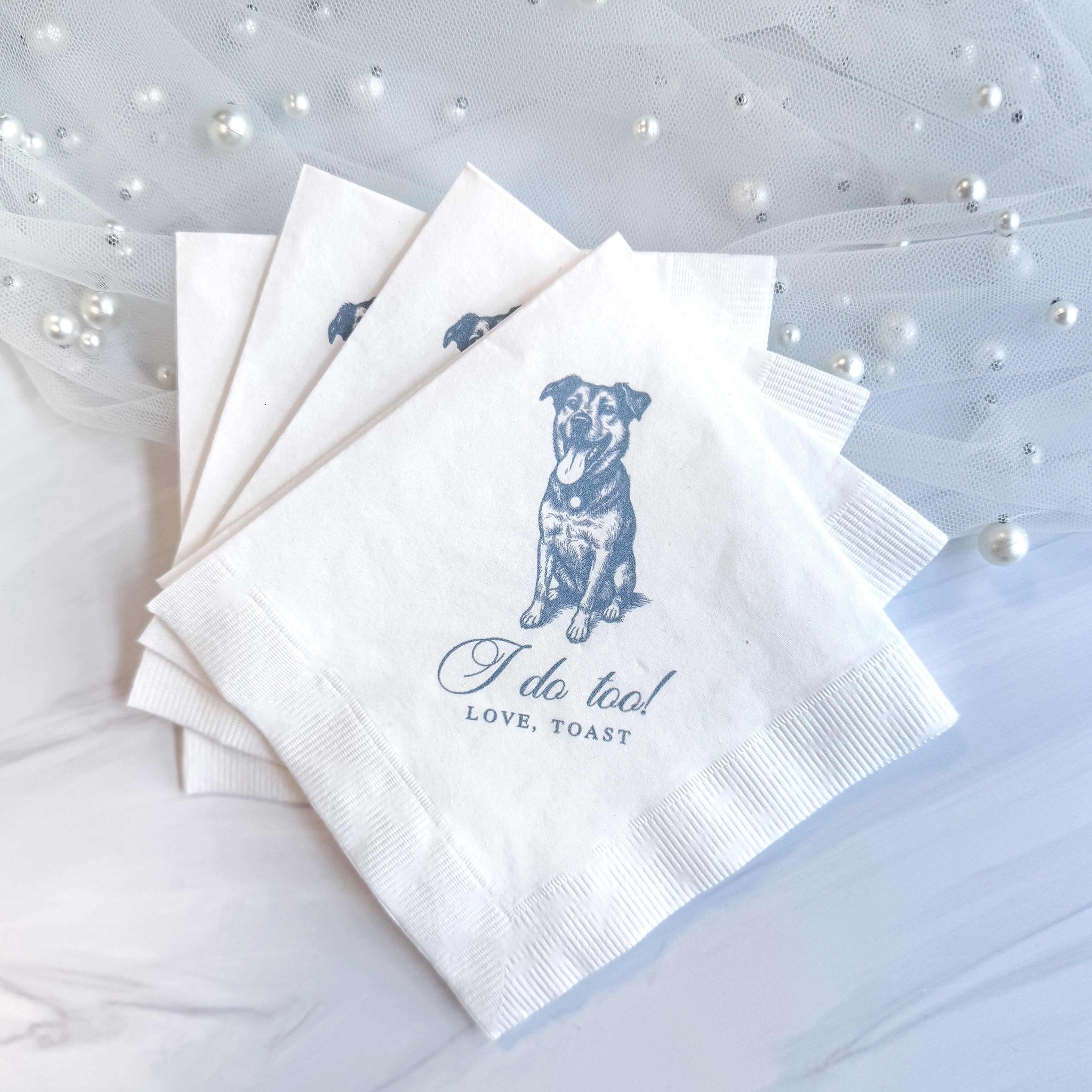White cocktail napkins with blue dog illustration and "Tail too! Love, [names]" personalization text