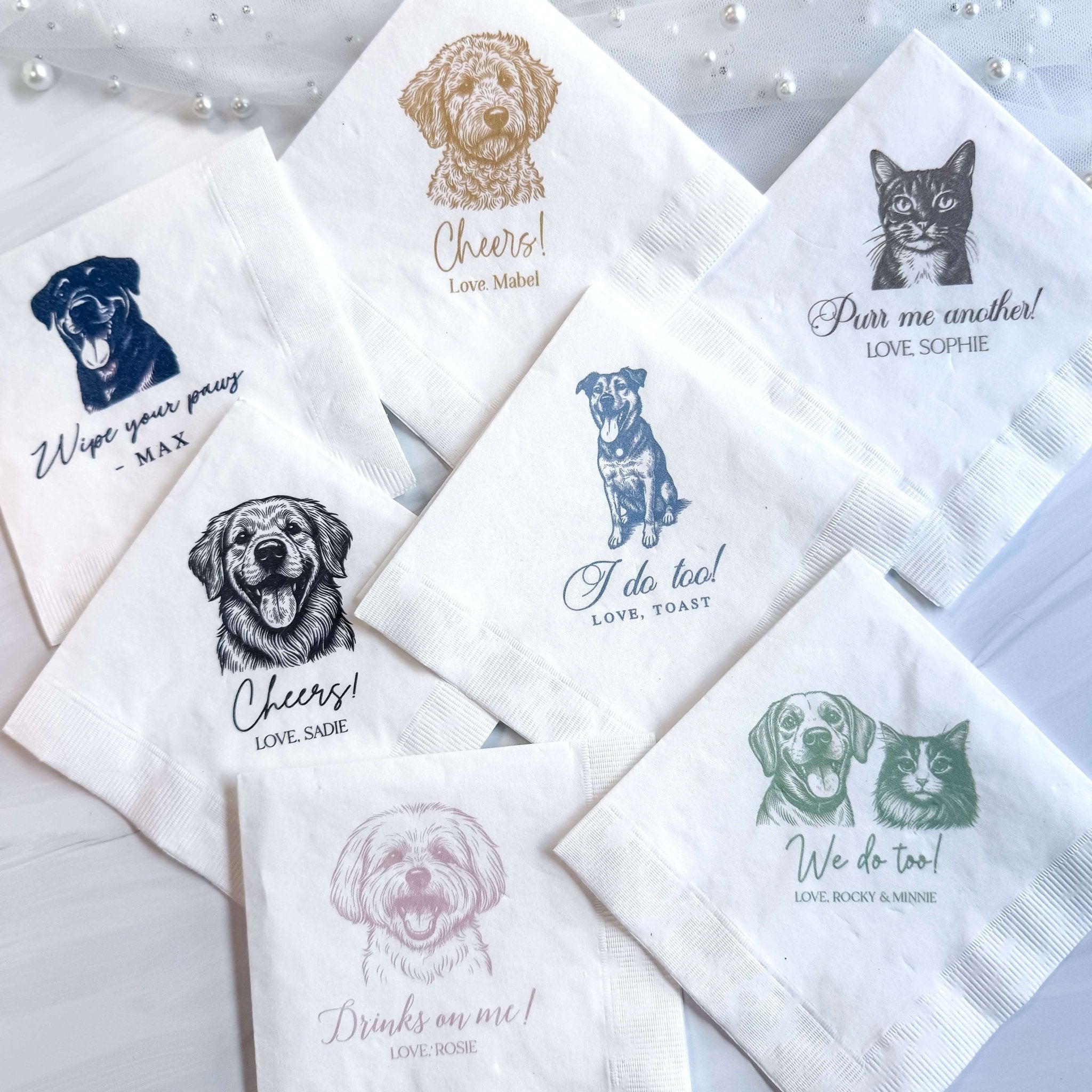 Set of white napkins with custom pet portraits and personalized text including dog and cat illustrations in various ink colors.