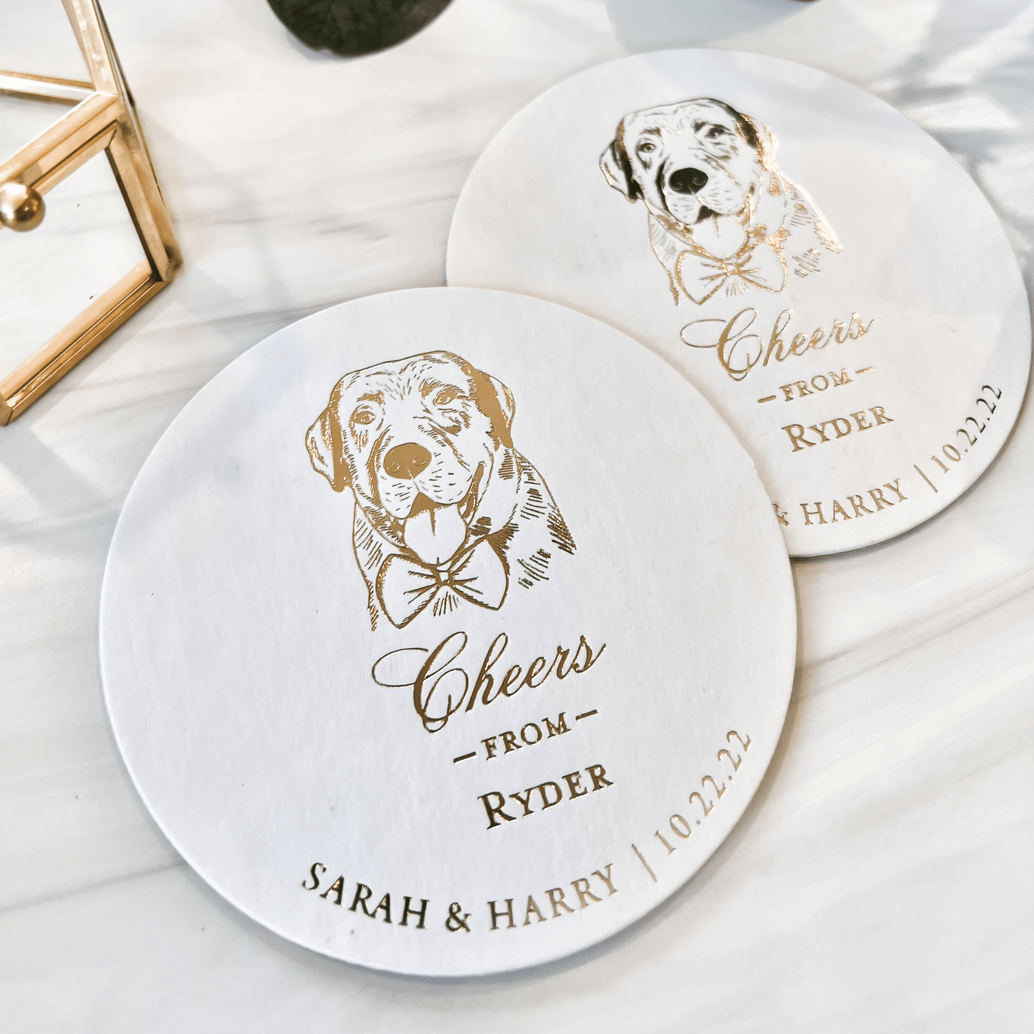 White ceramic coasters with gold dog illustrations and personalized text reading "Cheers from Rydel, Sarah & Harry 10.22.23"