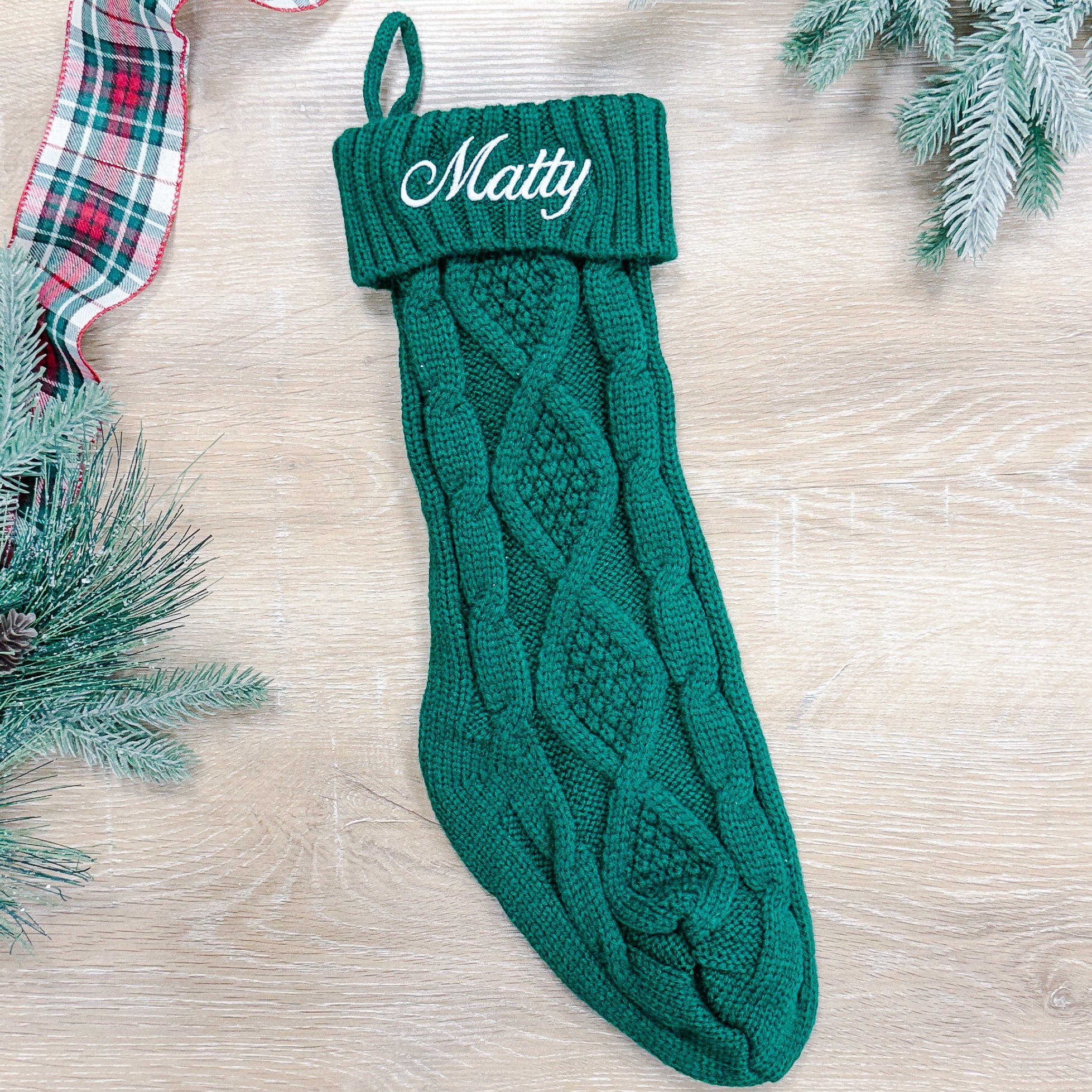 Green cable knit Christmas stocking with personalized "Matty" embroidered on cuff and hanging loop