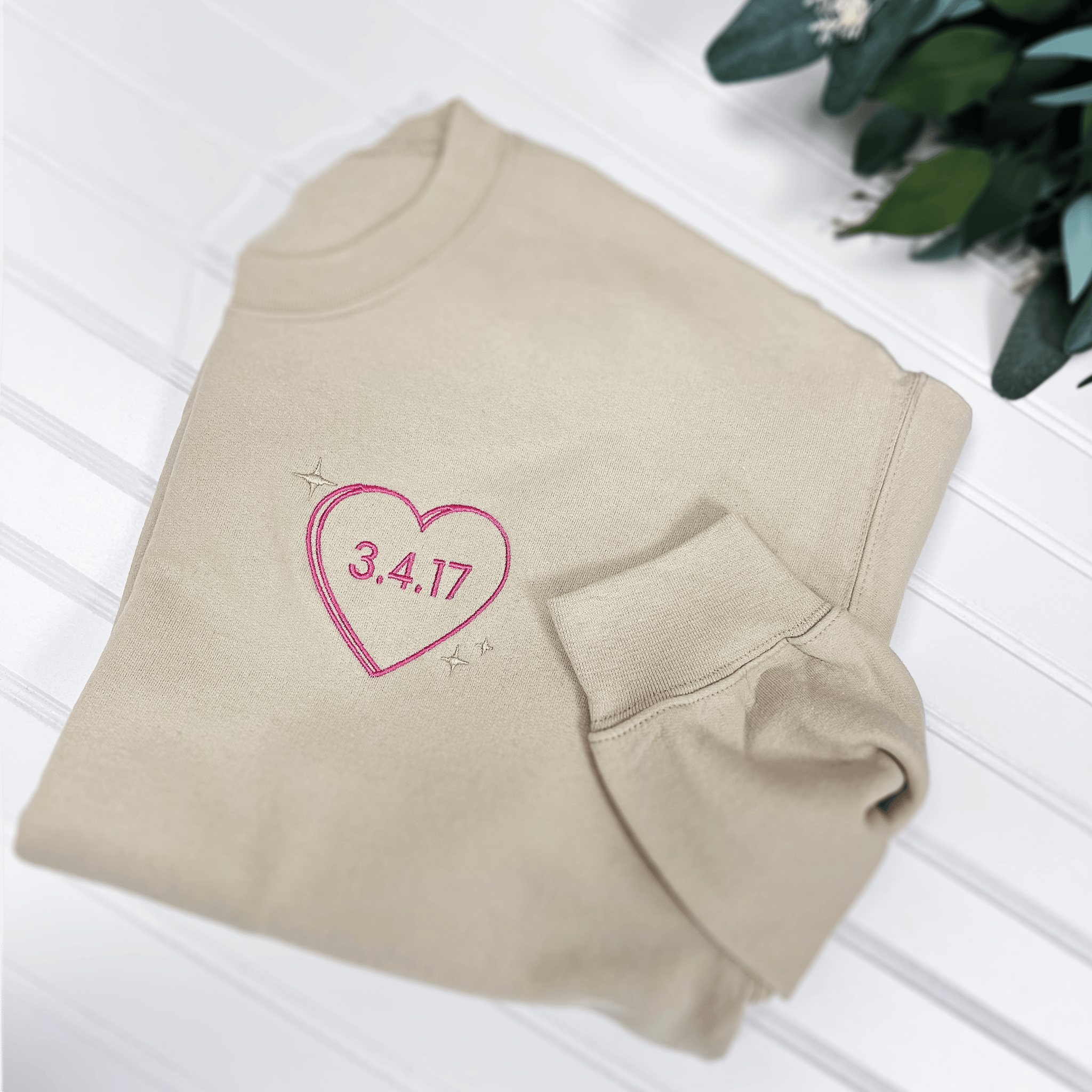 Cream colored sweatshirt with pink embroidered heart containing date "3.4.17" on chest