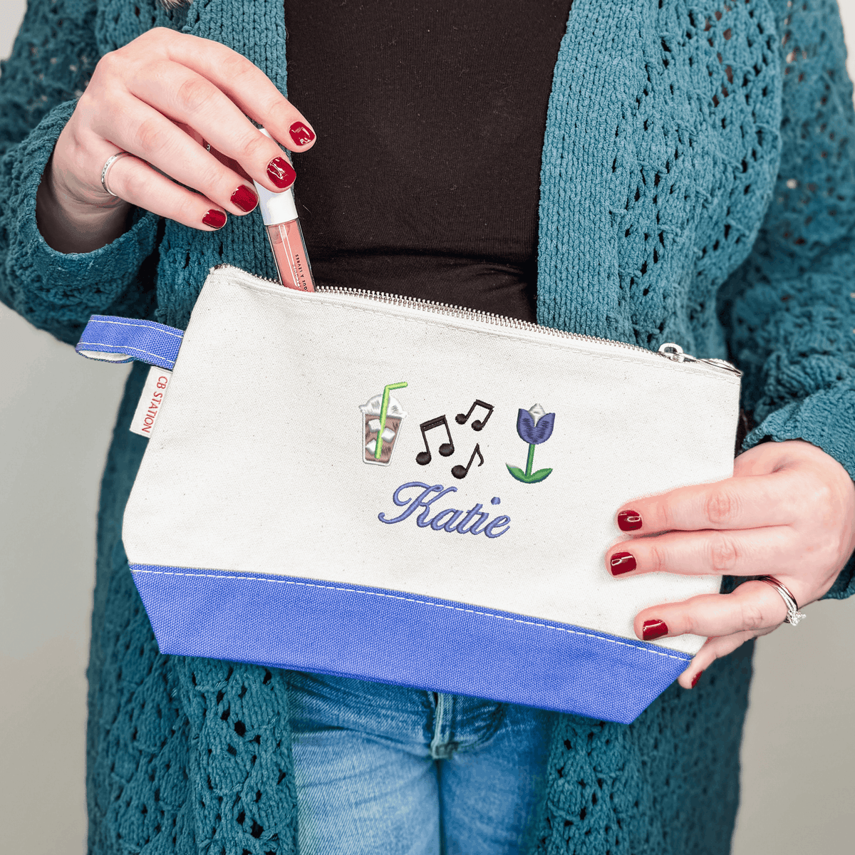 Custom cosmetic bag with periwinkle trim featuring iced coffee, music note and tulip icons with the name Katie in purple script
