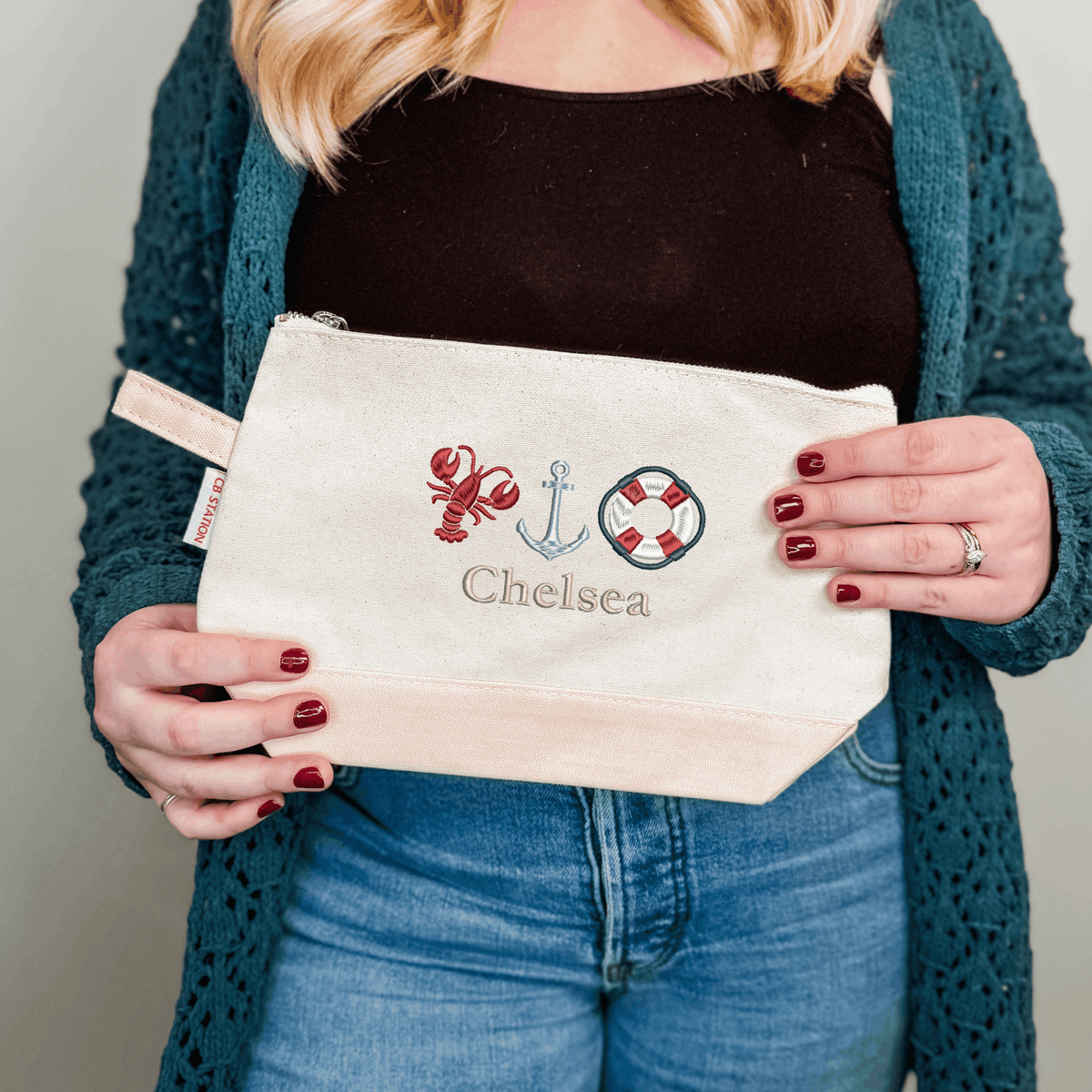 Personalized cosmetic bag with lobster, anchor and life ring icons and the name Chelsea, a nautical embroidered gift