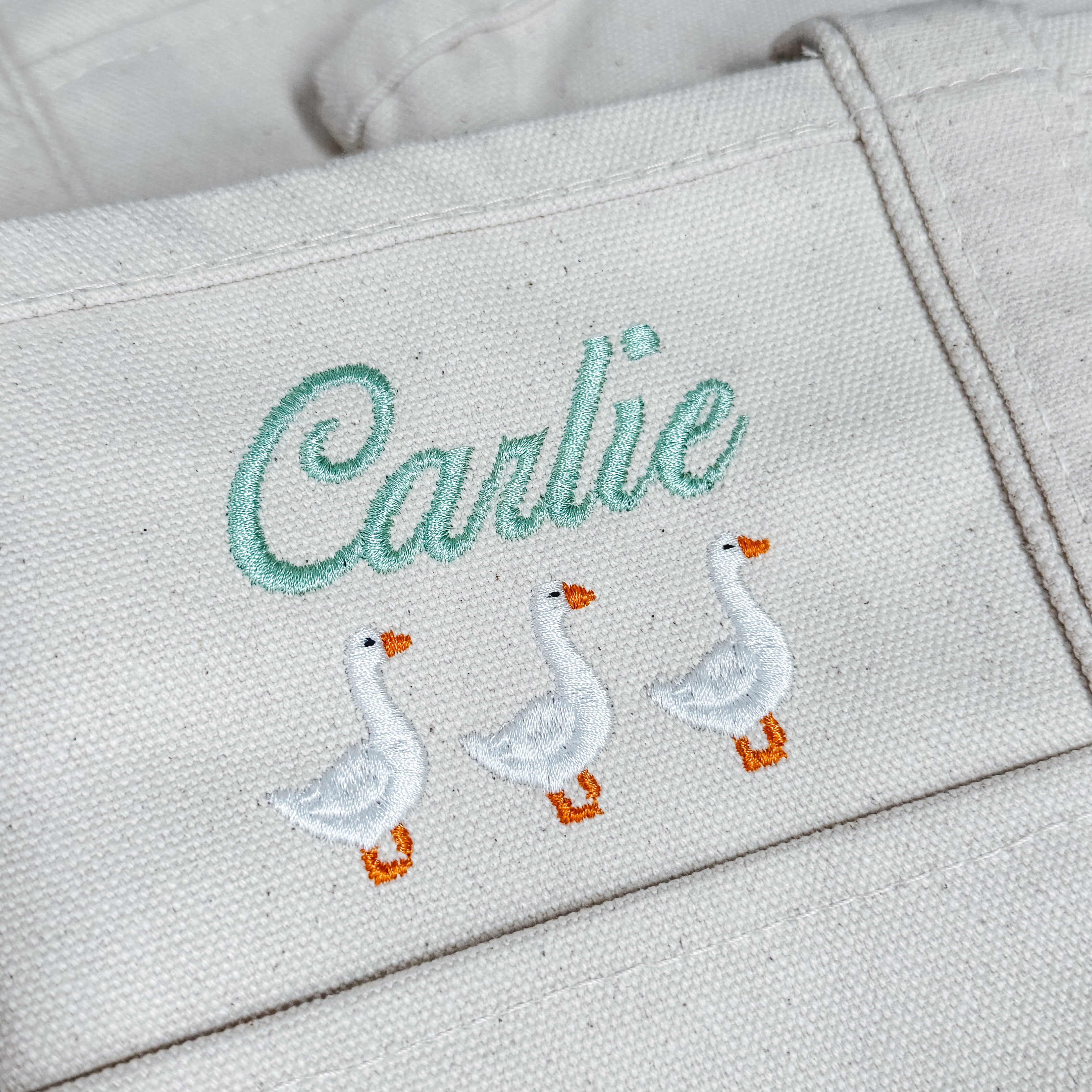 Personalized embroidered goose tote with the name Carlie in sage green script thread