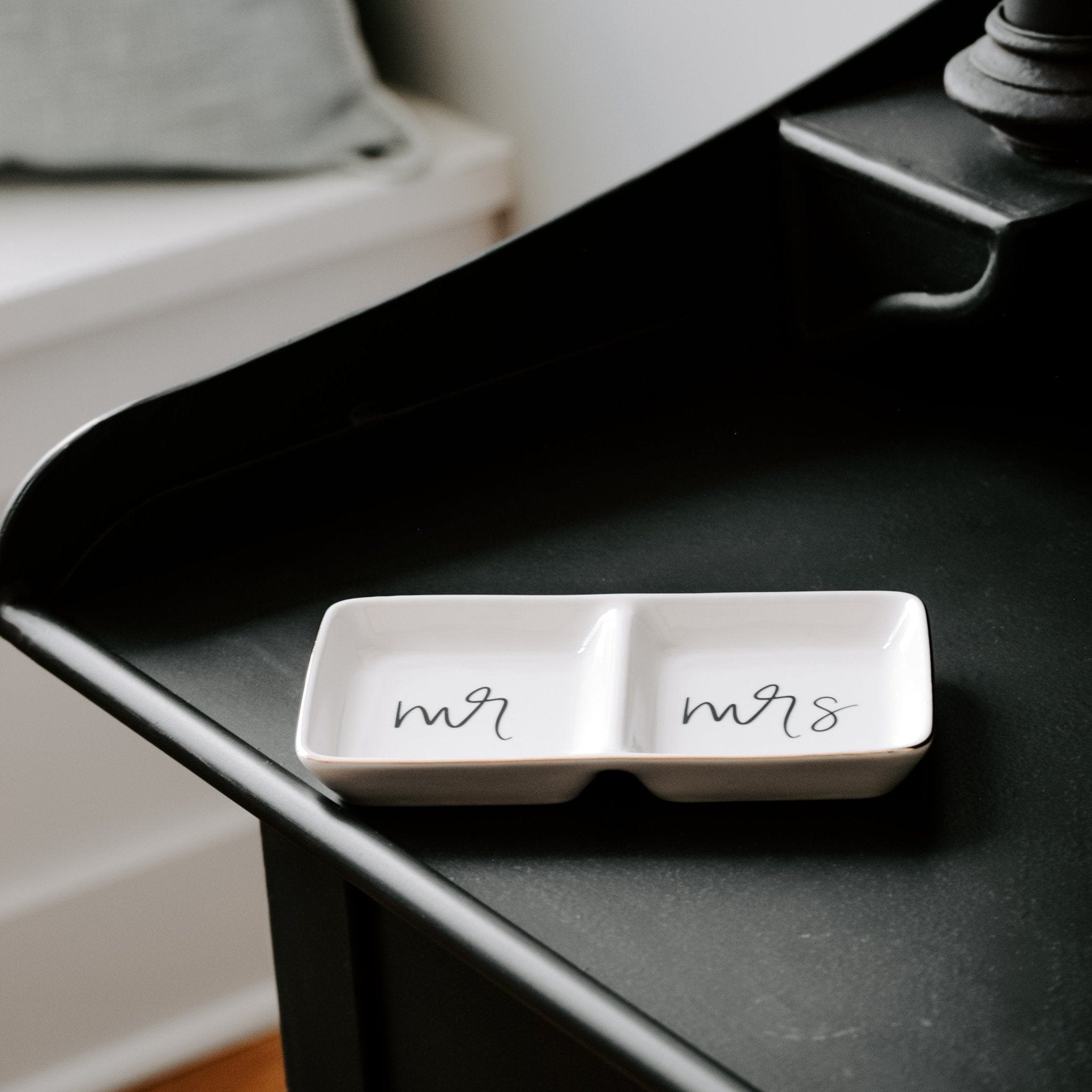 White ceramic jewelry dish with two compartments labeled "mr" and "mrs" on black surface