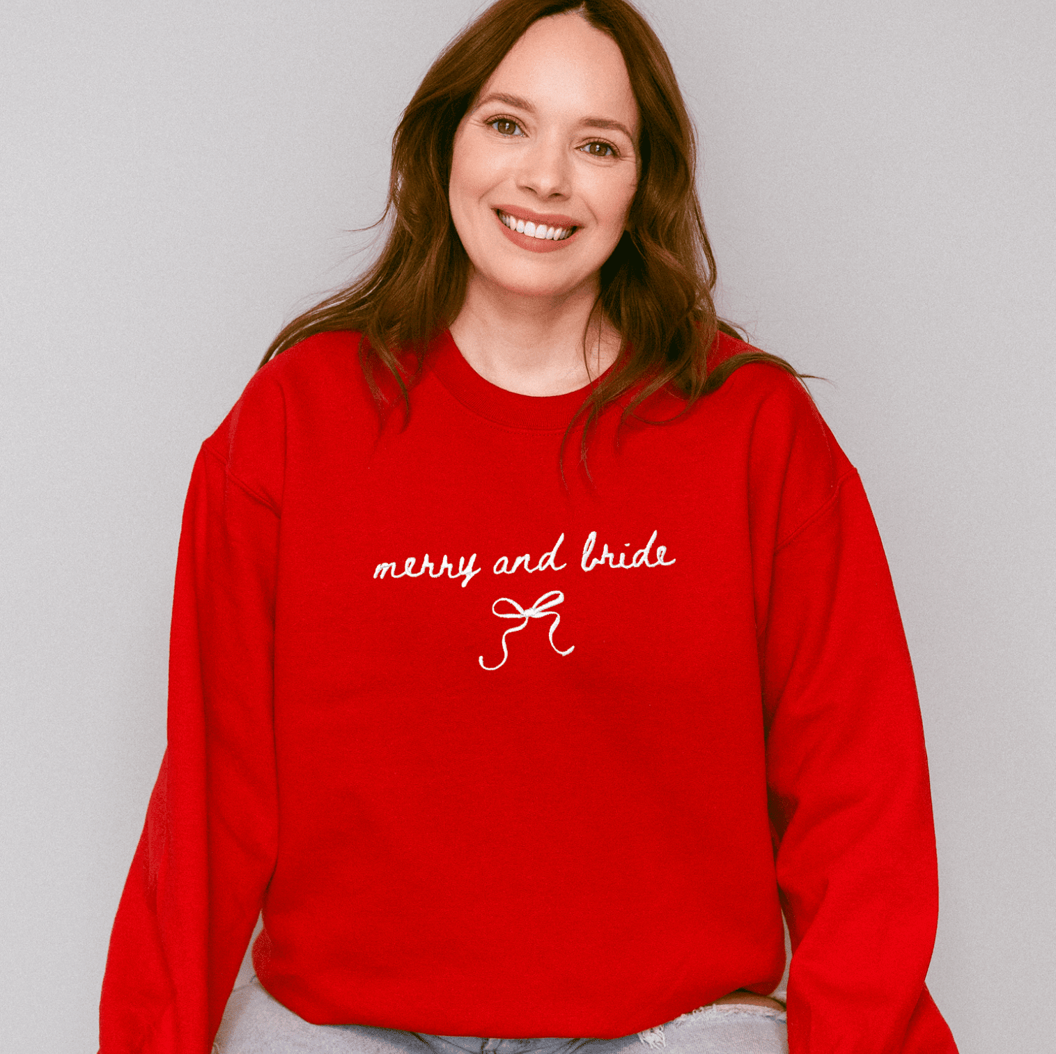 Red crewneck sweatshirt with "merry and bride" text and bow design in white embroidery on chest